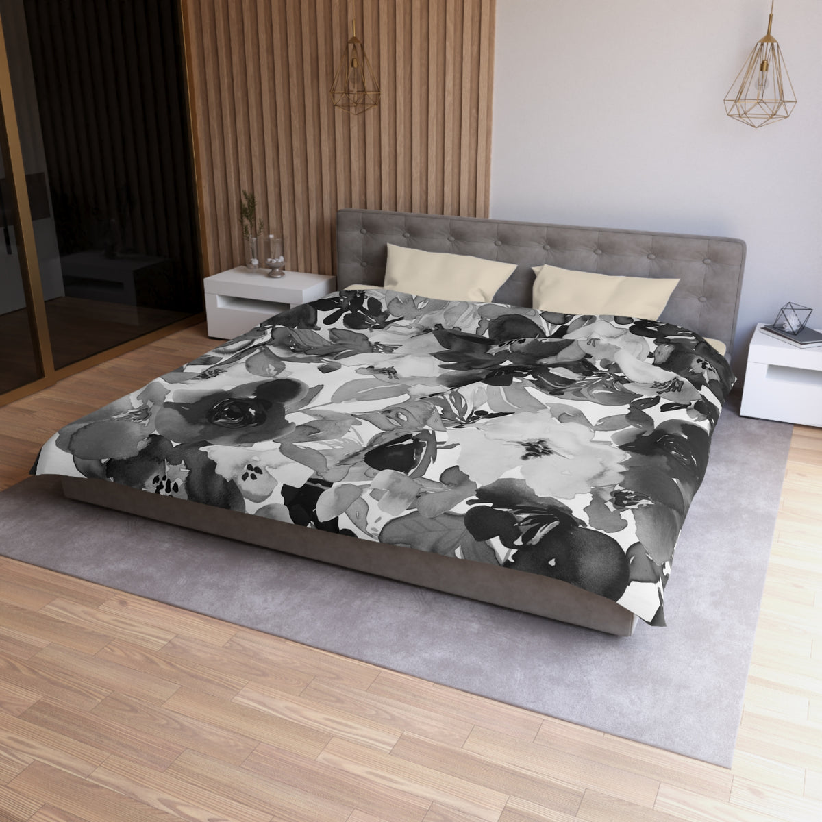 a modern bedroom with a large bed covered in a black and white floral print duvet cover. The bed is positioned against a wall with a wooden panel. The room also features a nightstand, a pendant light, and a rug on the floor.