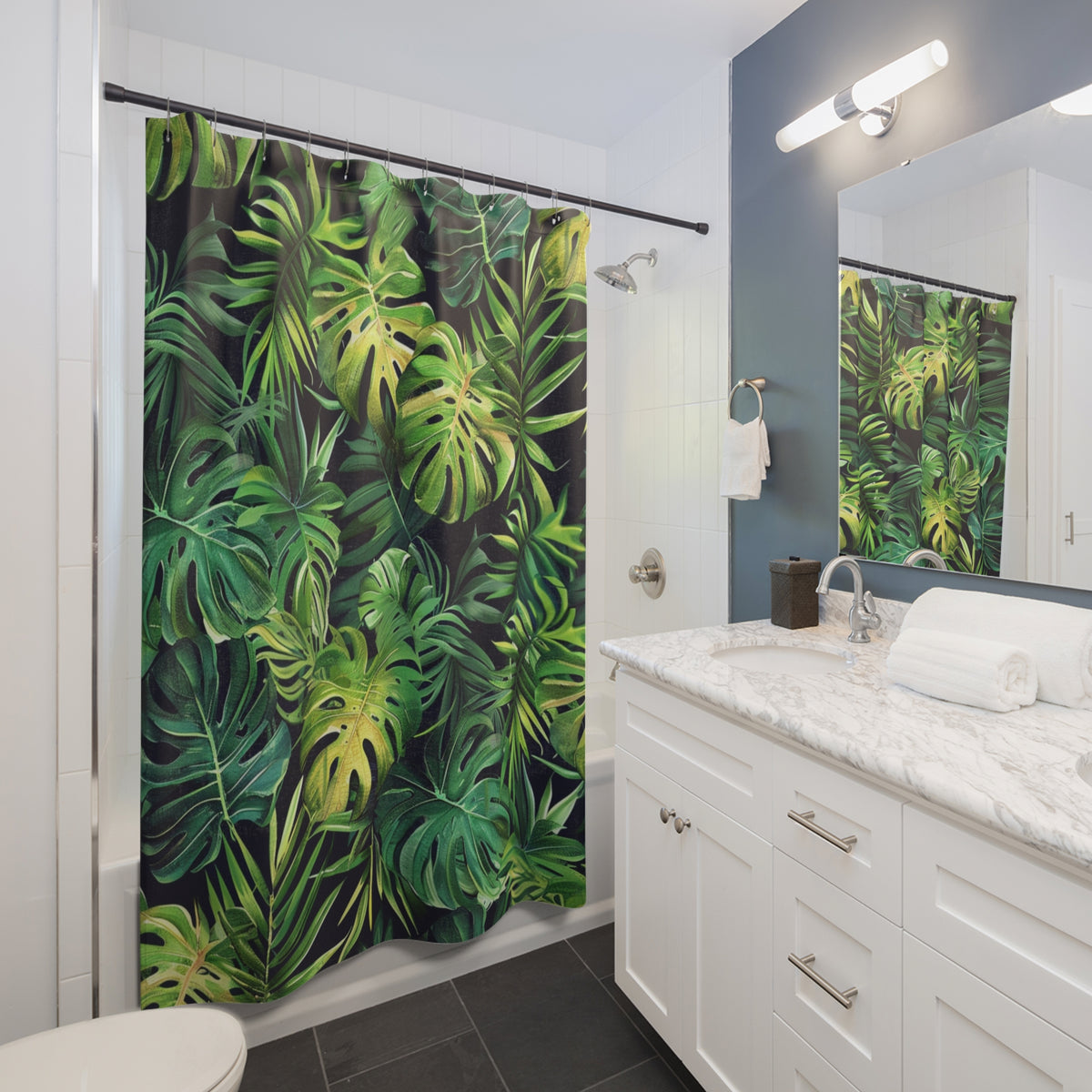 A bathroom with a shower curtain featuring a tropical plant design in shades of green and yellow. The bathroom has white cabinets, a marble countertop, and a large mirror.