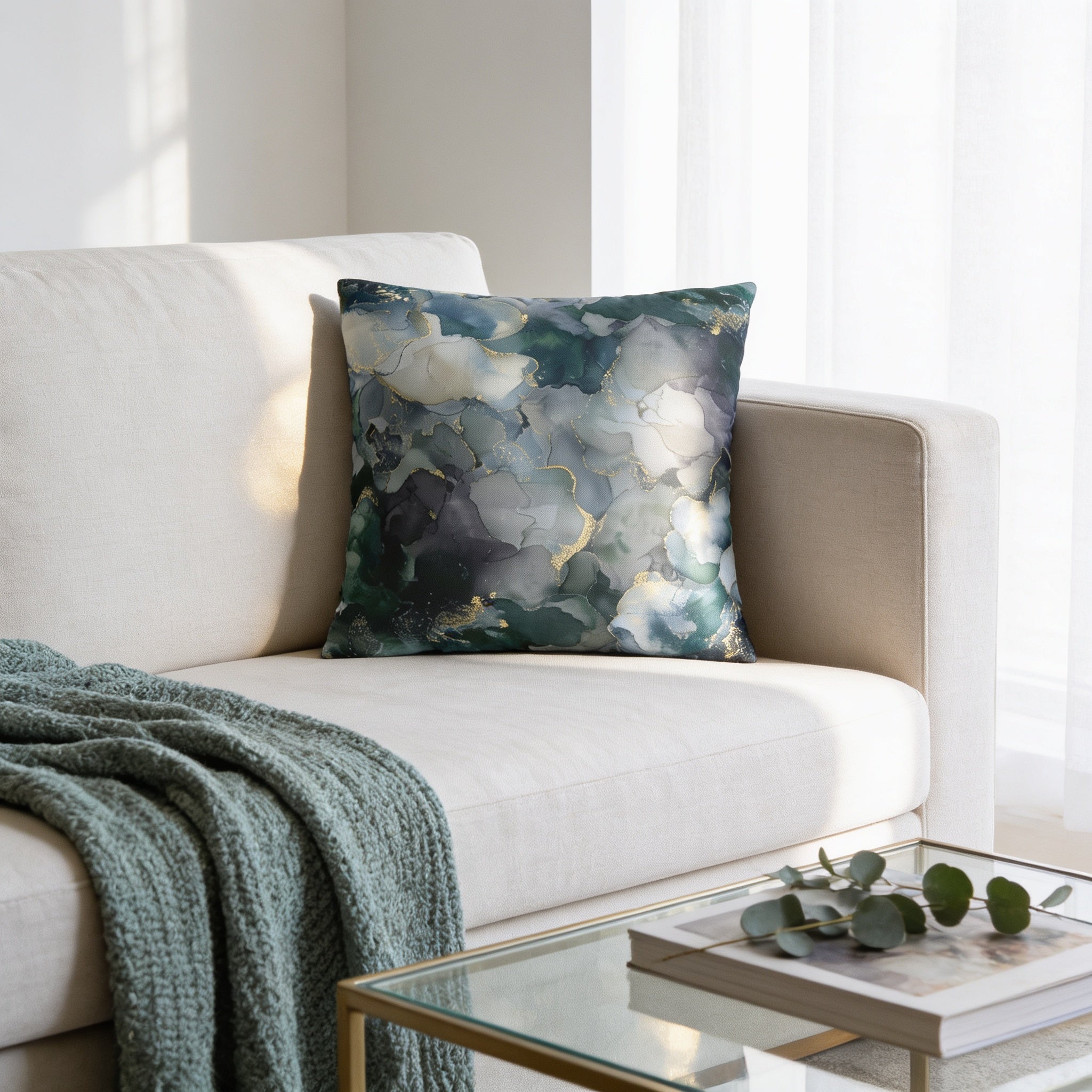 a cozy living room with a white sofa, a glass coffee table, and a throw blanket draped over the armrest. The throw pillow on the sofa has a colorful abstract pattern in shades of blue and green.