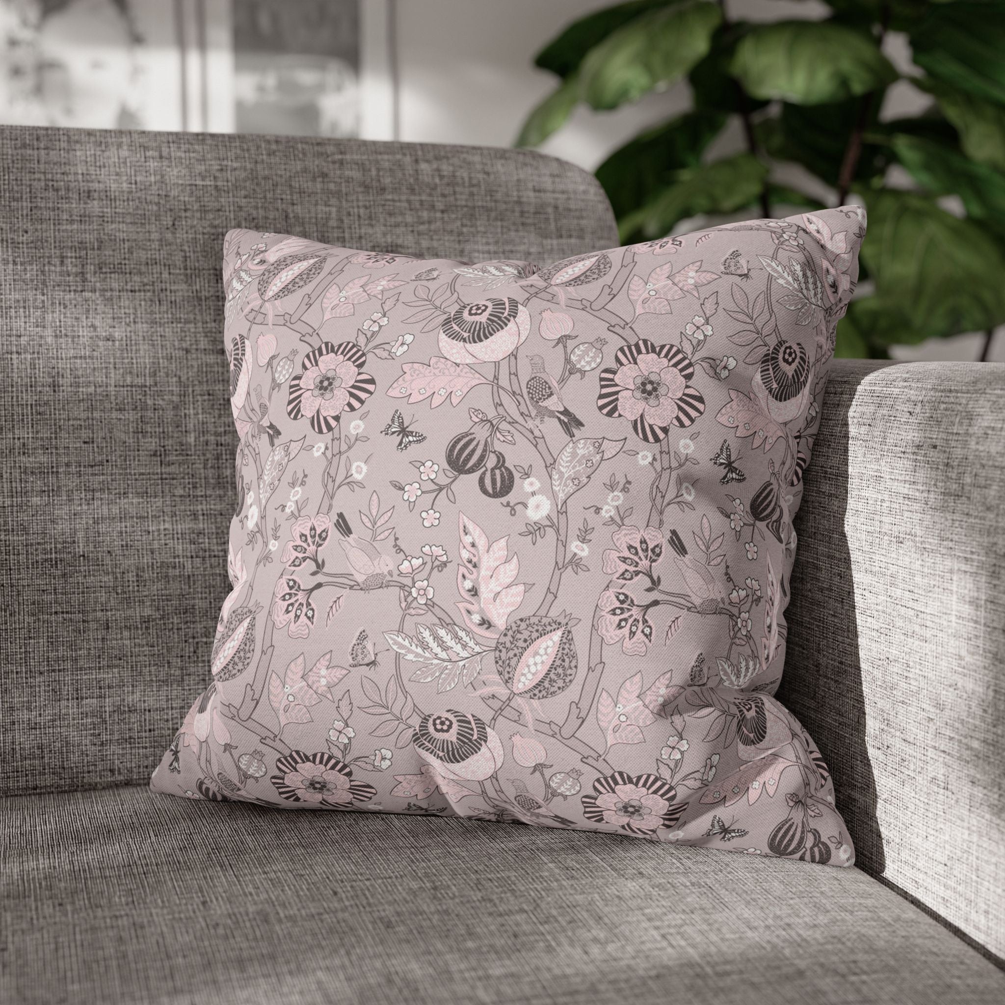 A gray sofa with a decorative pillow featuring a floral pattern in shades of pink and gray.