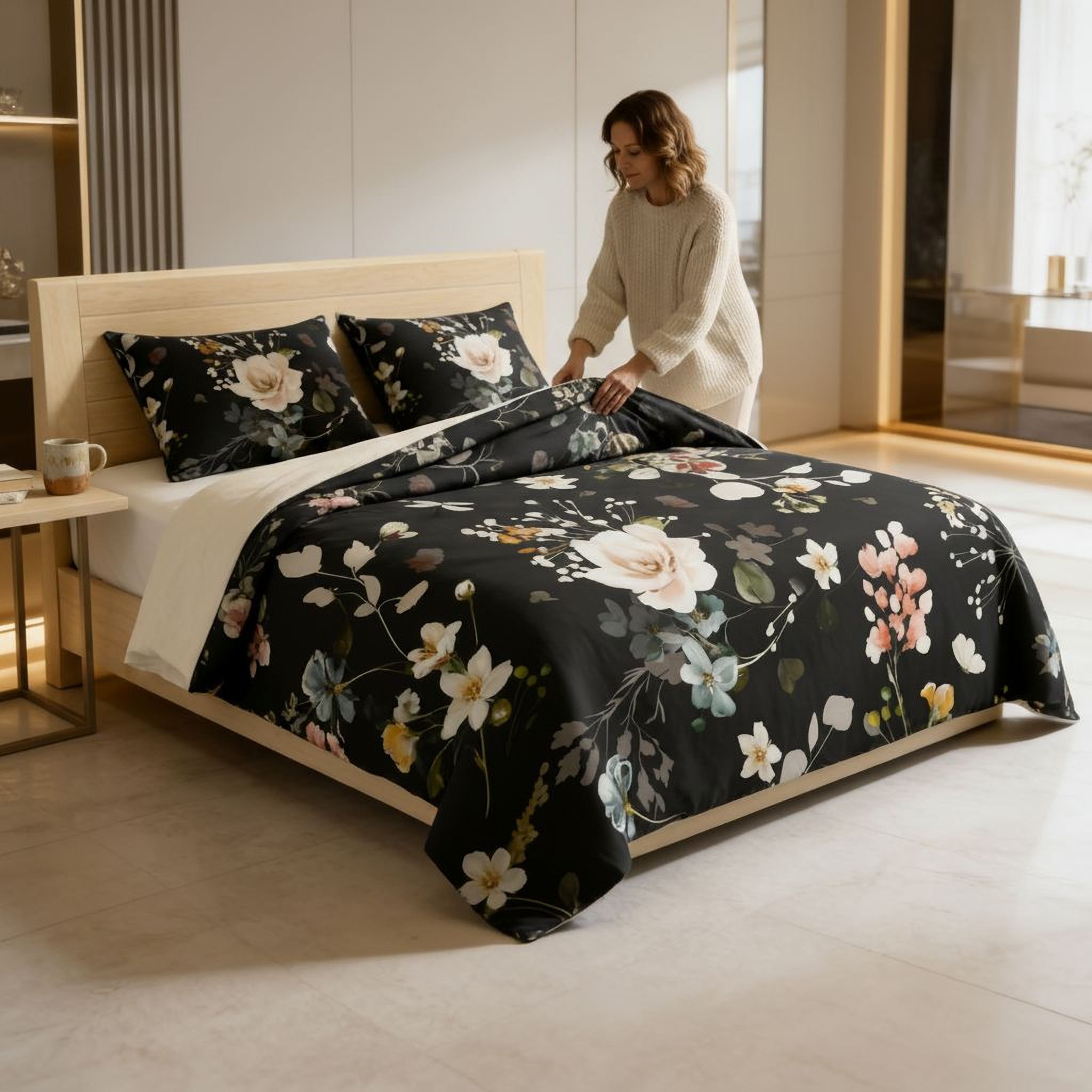 A woman is arranging a floral bedspread on a bed with a wooden headboard.