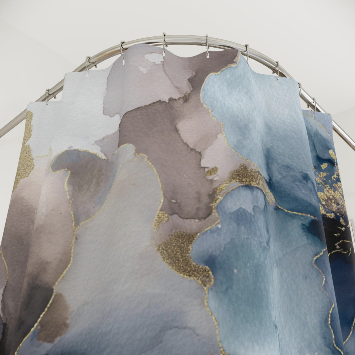 a shower curtain with a watercolor-style abstract design in shades of blue, gray, and brown, with gold accents.