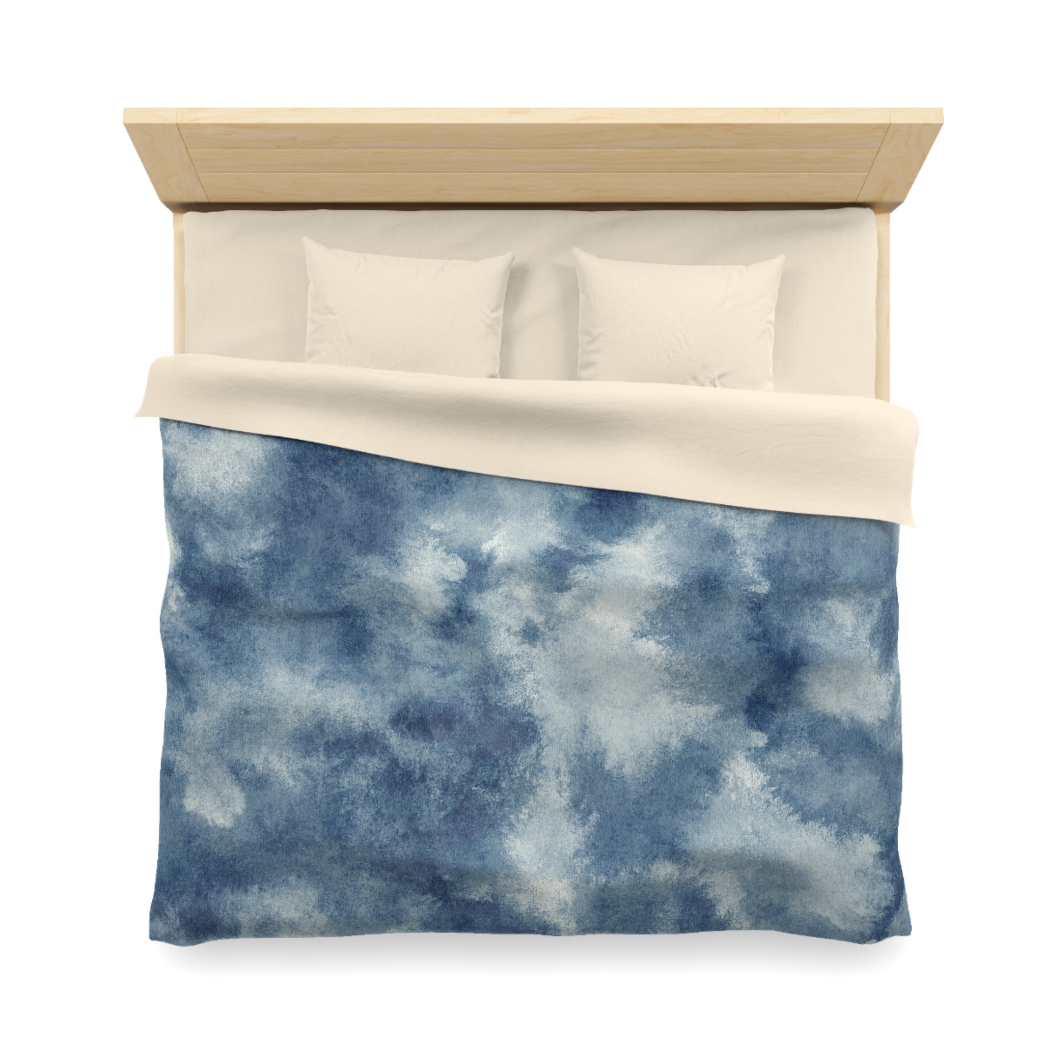 A neatly made bed with a blue and white patterned comforter and two white pillows.