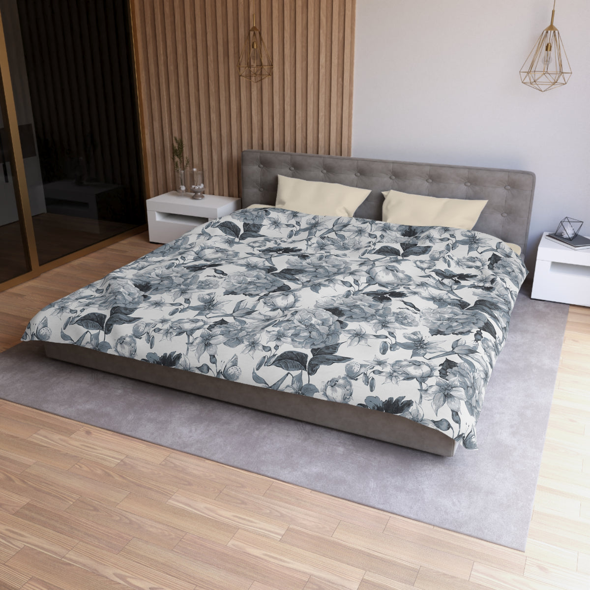 a modern bedroom with a large bed, a gray headboard, and a floral patterned comforter. The room has a wooden floor and white walls, creating a serene and elegant atmosphere.