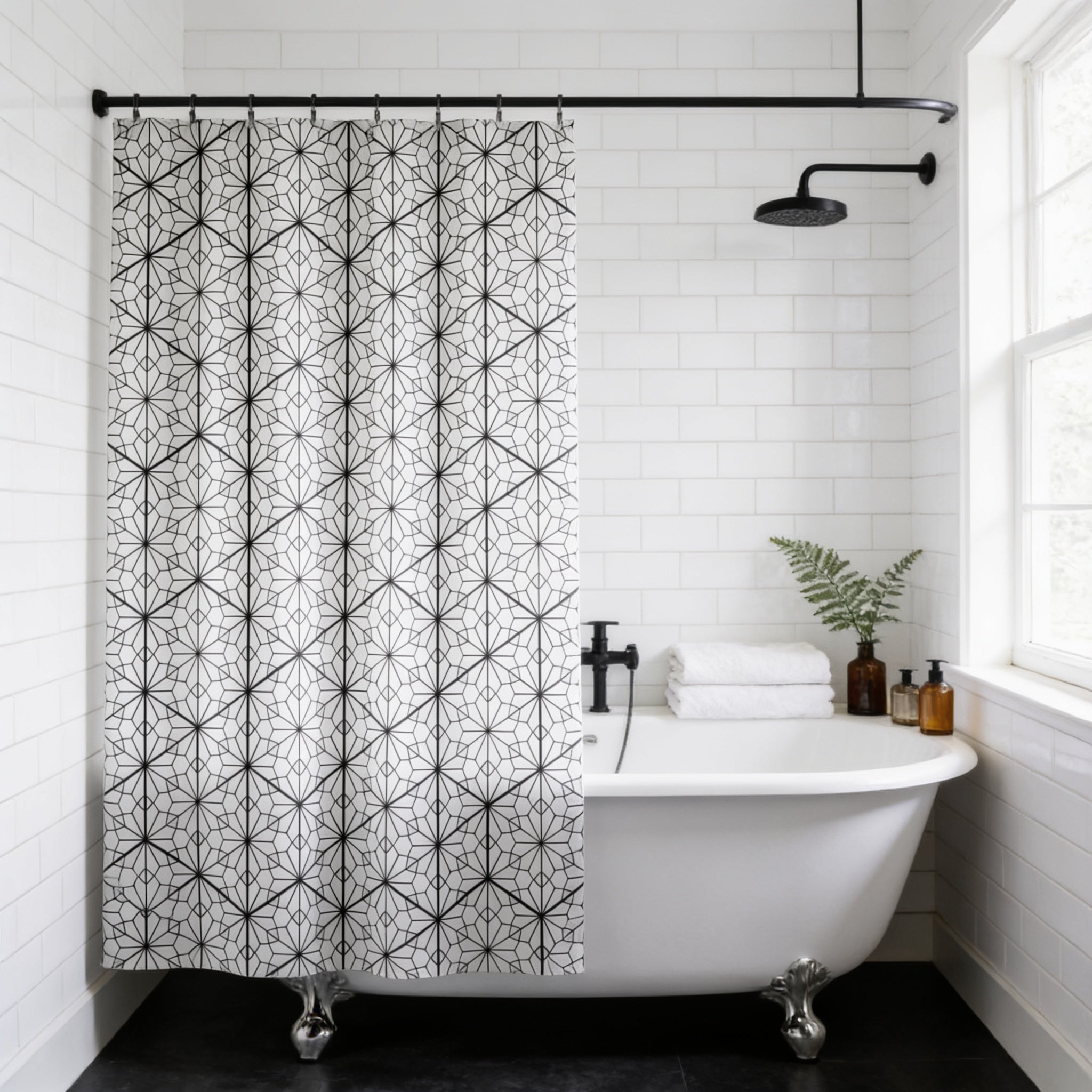 A modern bathroom with a white clawfoot bathtub, a black and white patterned shower curtain, and a window above the bathtub.