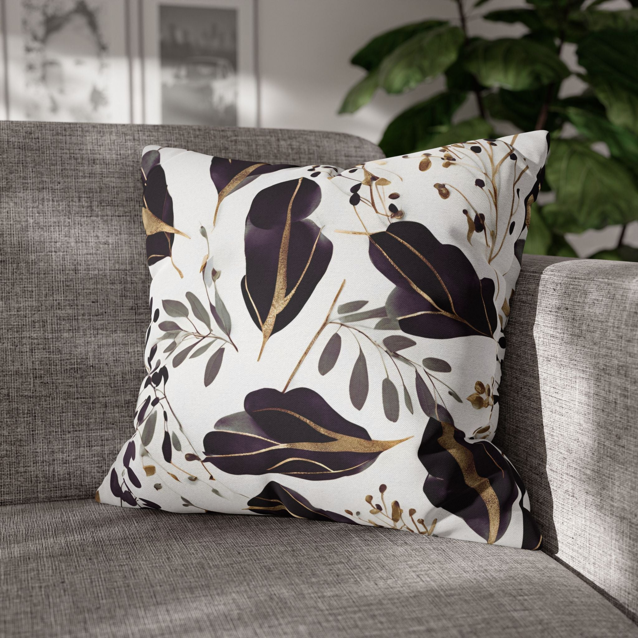 A decorative throw pillow with a floral pattern sits on a gray couch, with a plant visible in the background.