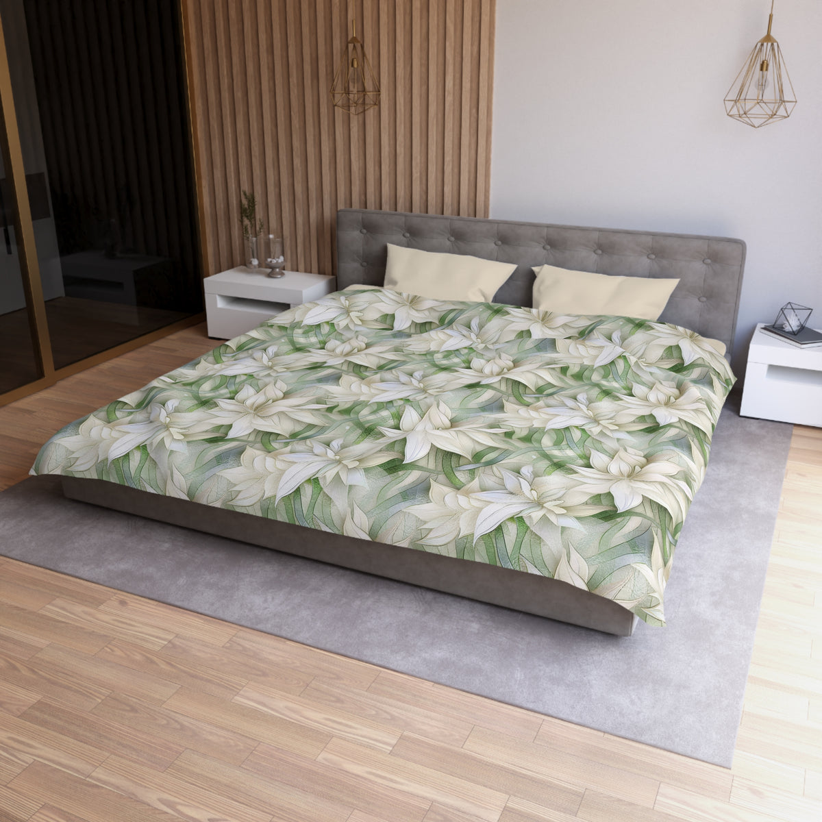 a modern bedroom with a large bed covered in a floral print comforter. The bed is positioned against a wall with a wooden panel. The room has a minimalist design, with a gray headboard and white nightstands. There is a pendant light hanging above the bed, and a vase on one of the nightstands. The overall color scheme of the room is neutral, with the floral print adding a touch of nature and color.