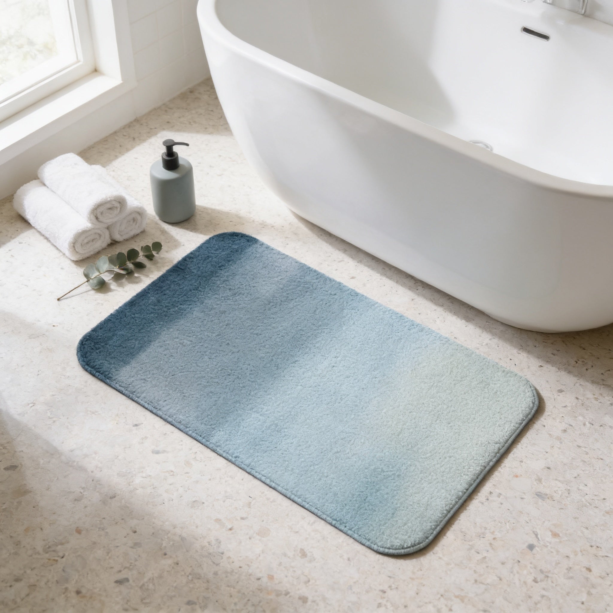 a bathroom with a white bathtub, a blue bath mat, and a bottle of soap on the floor.