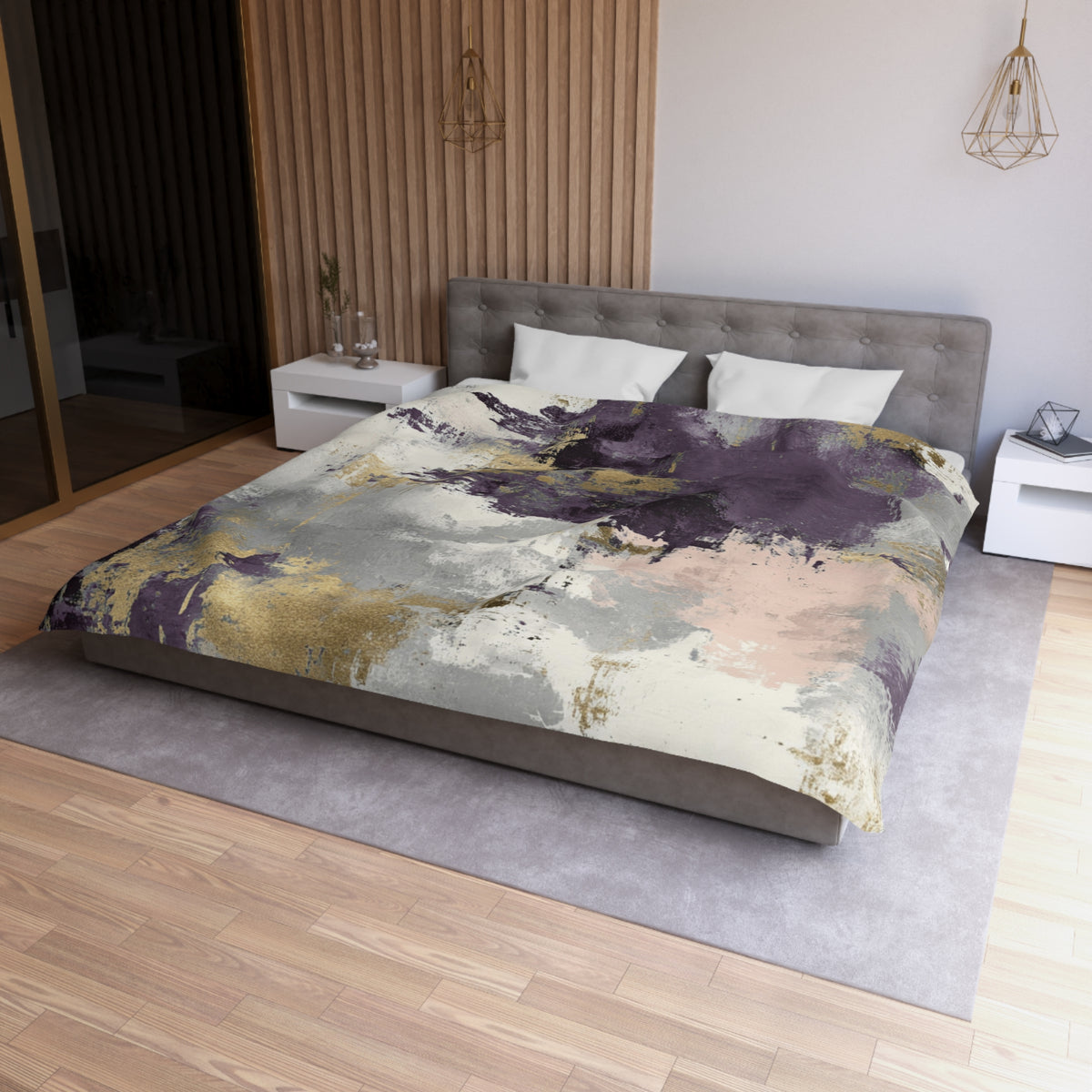 a modern bedroom with a large bed, a gray headboard, and a colorful abstract patterned comforter. The room has a wooden floor and white walls, creating a clean and minimalist aesthetic.