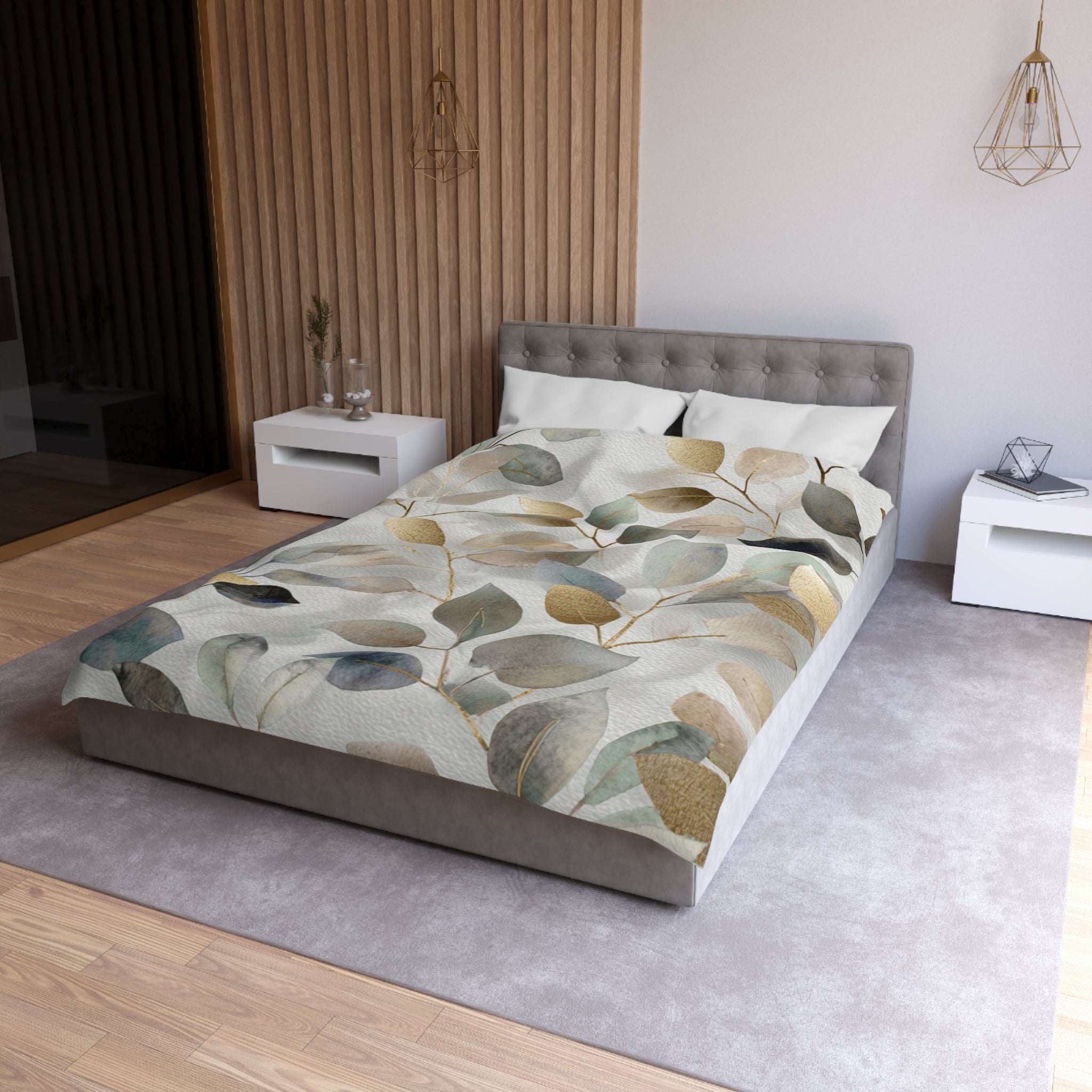 a modern bedroom with a gray tufted headboard, a gray bedspread with a leaf pattern, and white nightstands on either side of the bed.