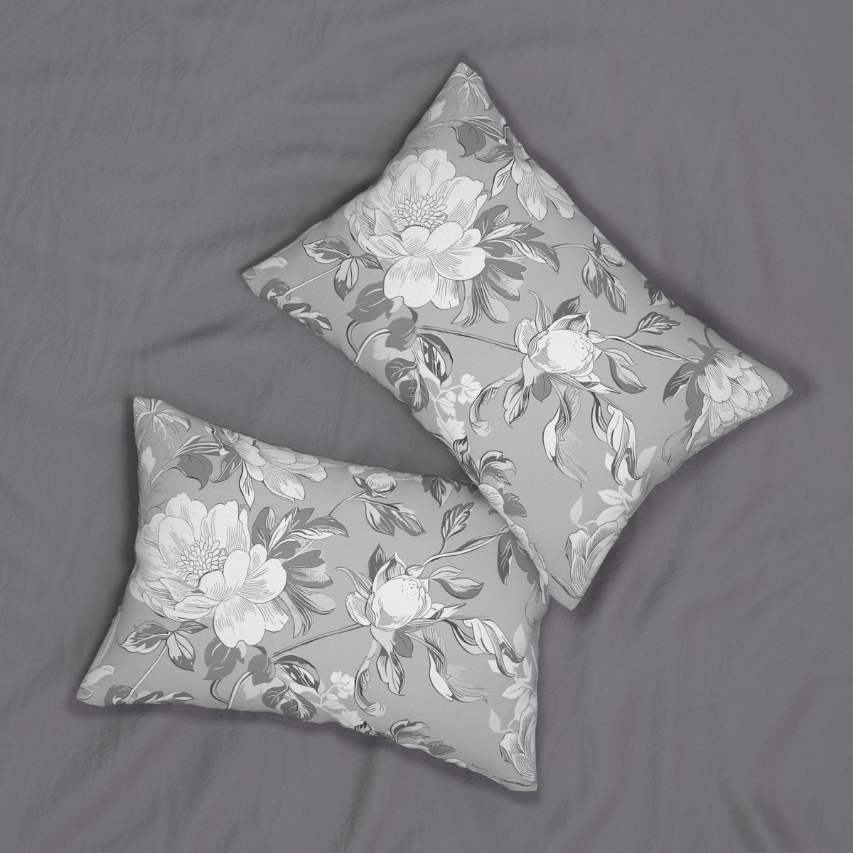 two gray and white floral patterned pillows placed on a gray bedspread.
