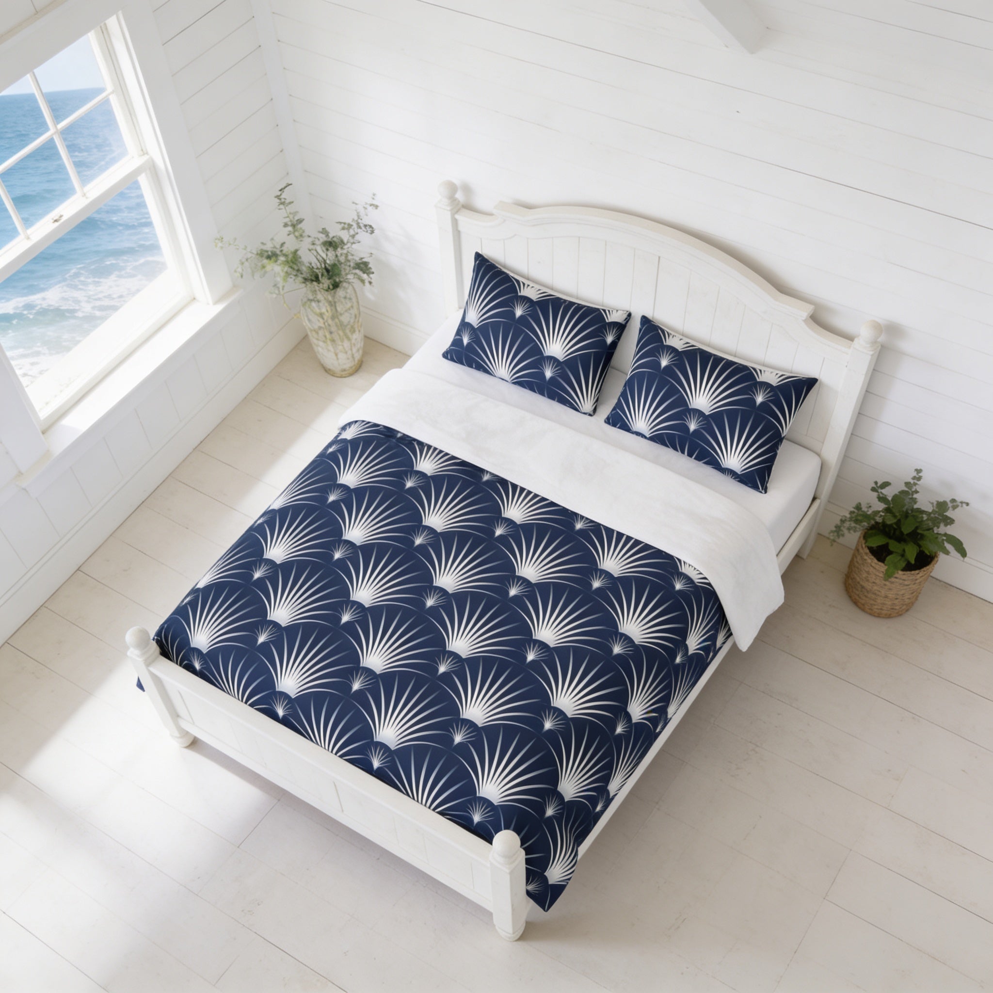 a bedroom with a white wooden bed frame, a blue and white patterned comforter, and two matching pillows. The room has a window overlooking the ocean, and there are two potted plants on either side of the bed.