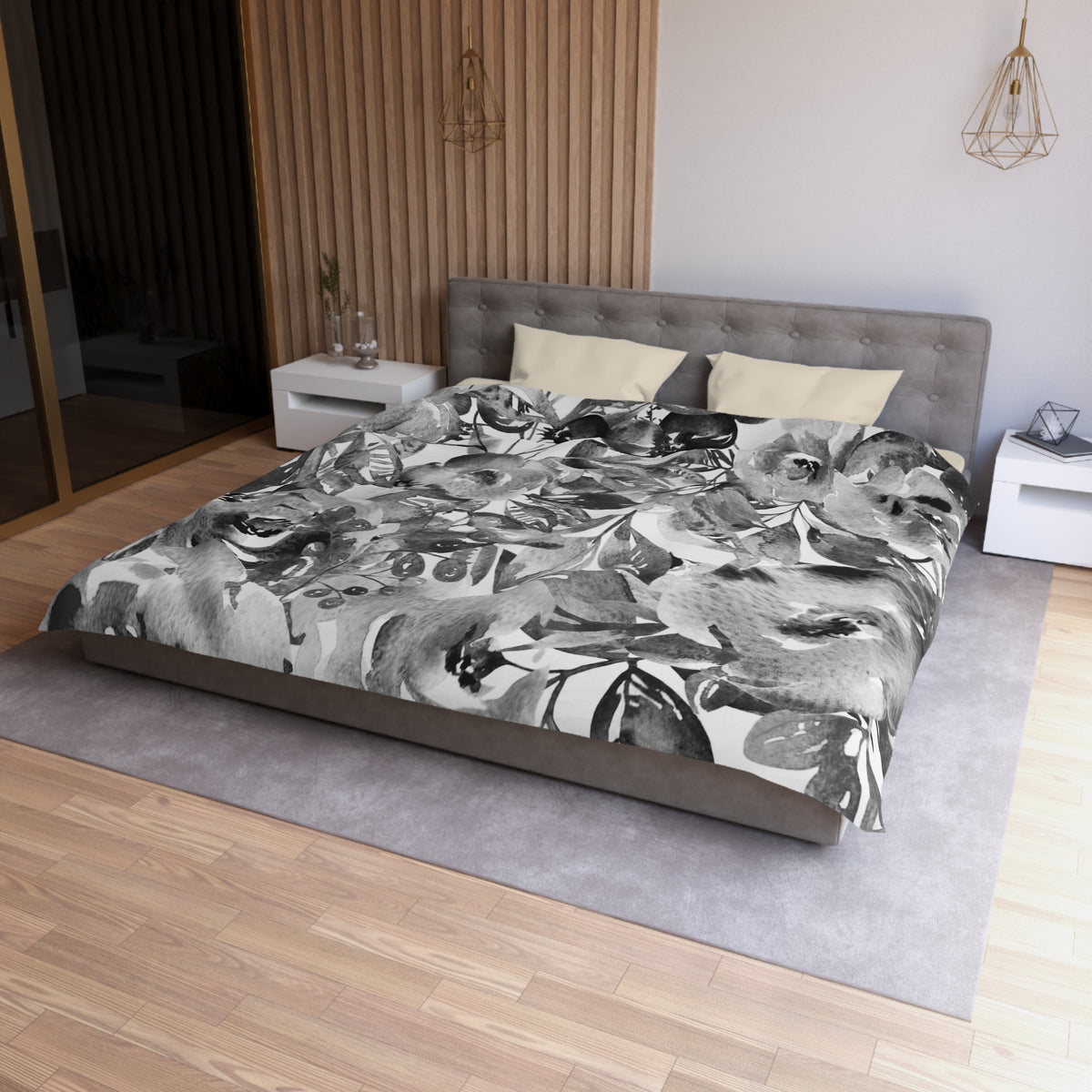 a modern bedroom with a large bed covered in a black and white floral patterned comforter. The bed is positioned against a wall with a wooden paneling. The room also features a nightstand, a pendant light, and a rug on the floor.