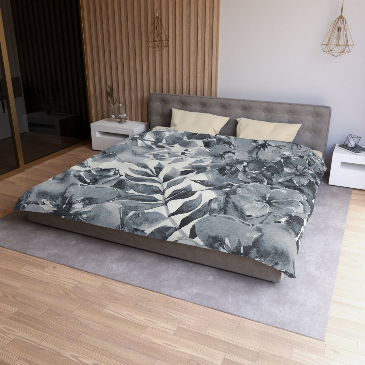 a modern bedroom with a large bed, a gray headboard, and a gray and white floral comforter. The room has a wooden floor and white walls, creating a serene and elegant atmosphere.