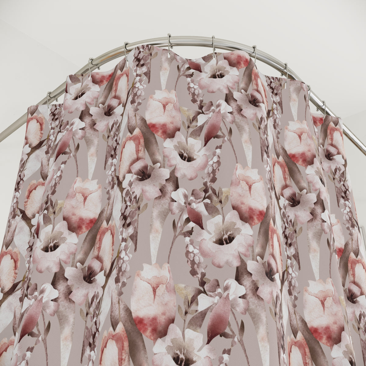 a shower curtain with a floral pattern, featuring pink and white flowers and leaves. The curtain is hanging from a metal rod, and the background appears to be a white wall.