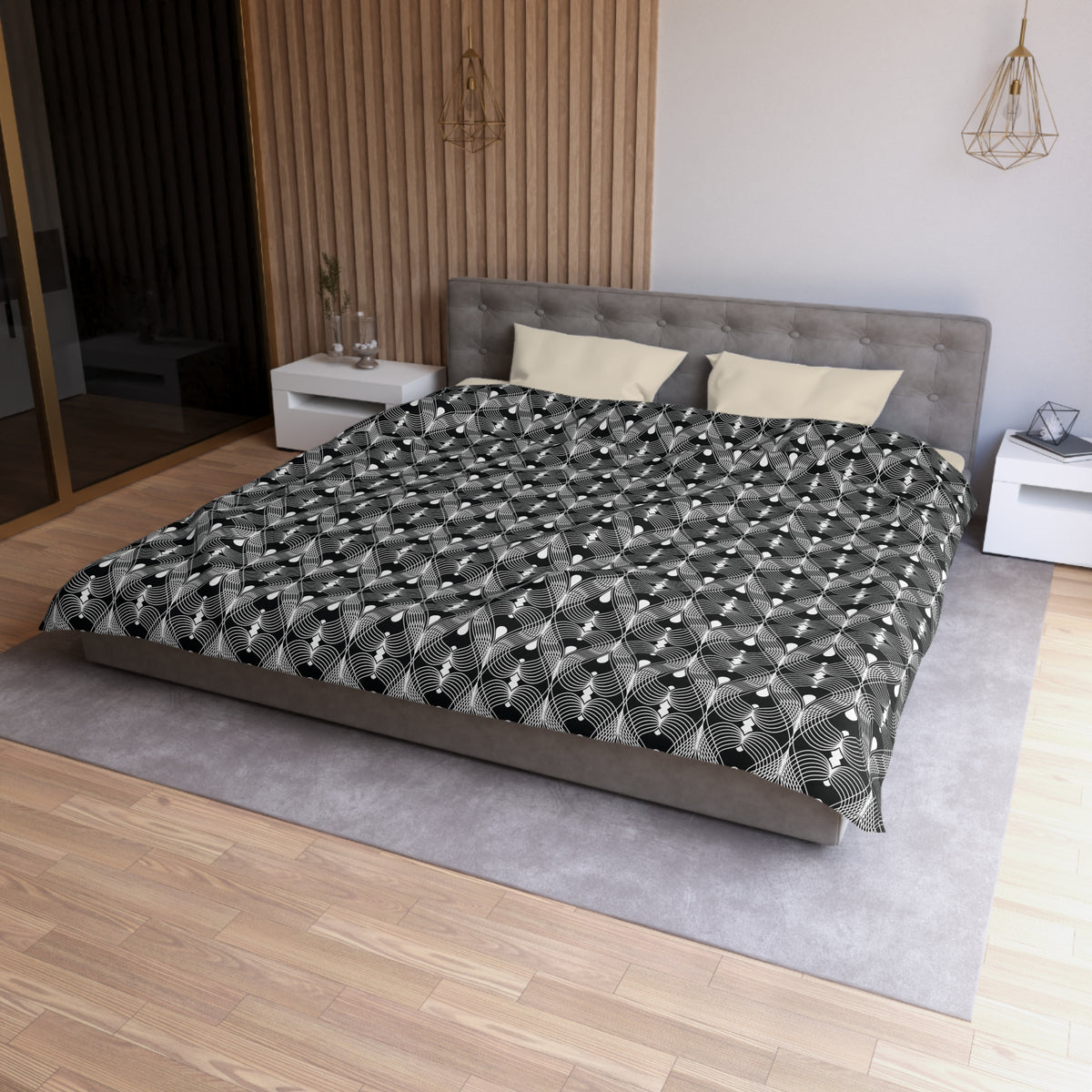 a modern bedroom with a large bed, a gray headboard, and a black and white patterned comforter. The room has a wooden floor and white walls, creating a clean and minimalist aesthetic.