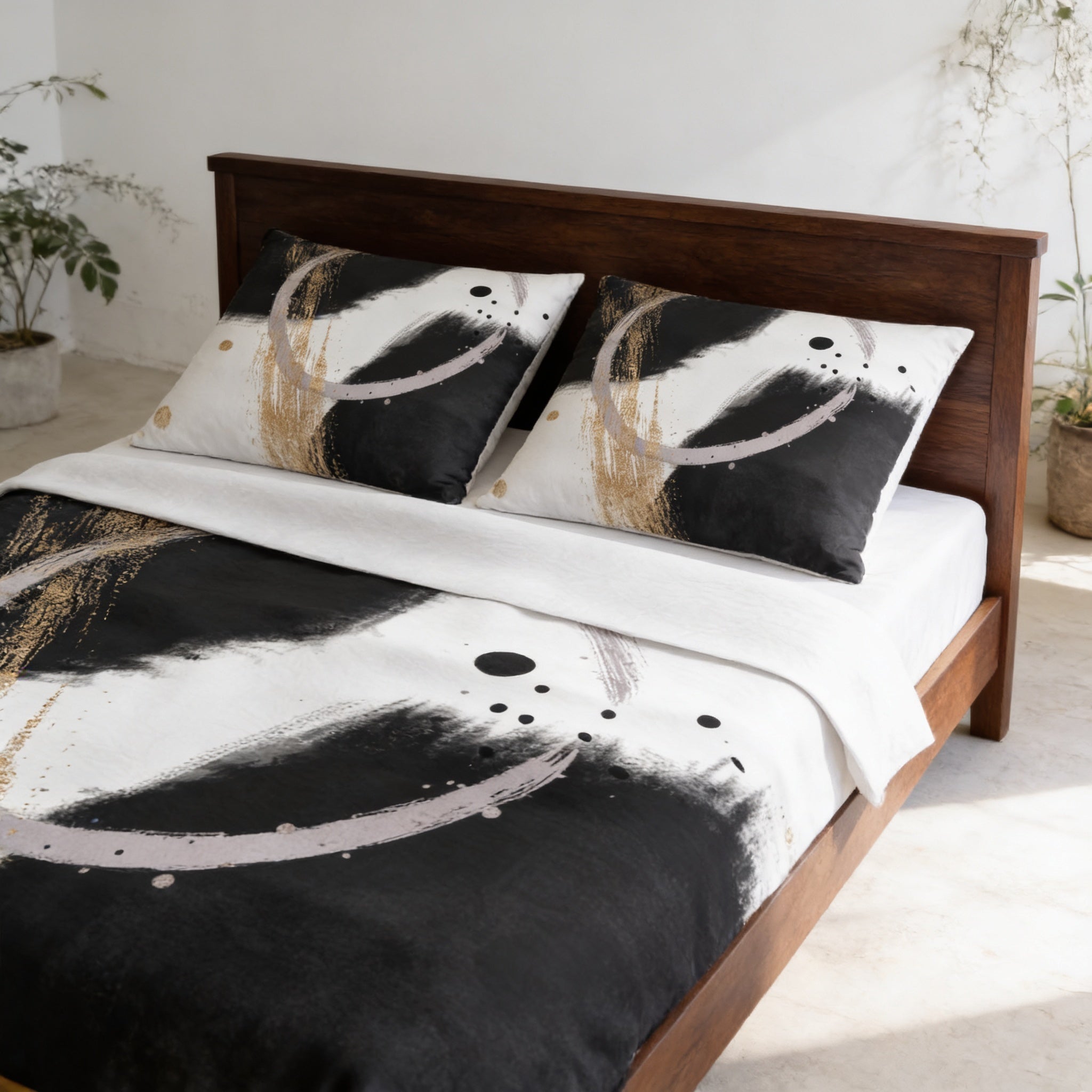 a bed with a black and white abstract patterned comforter and matching pillows. The bed is set against a white wall, and there are some plants in the background.