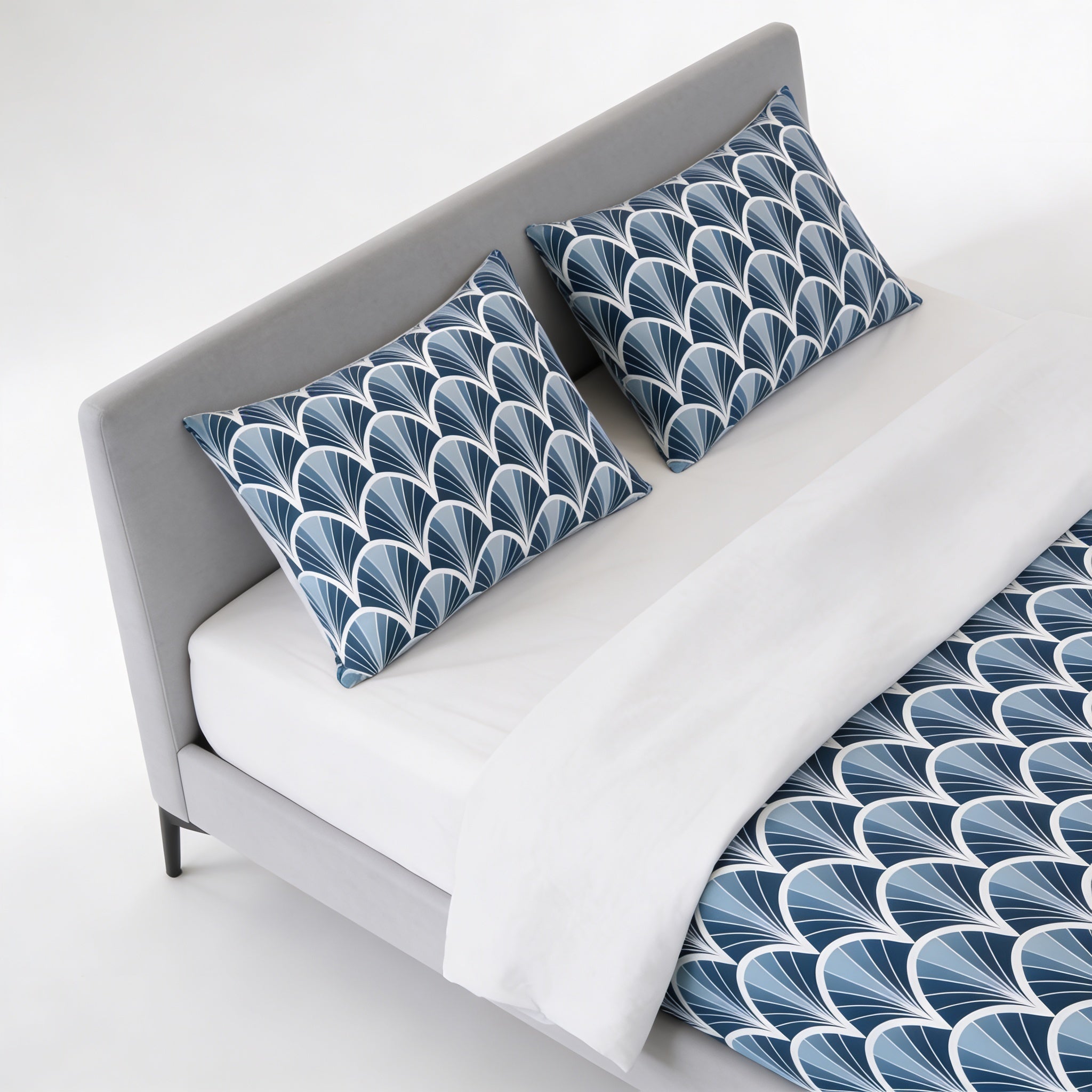 a modern, gray bed with a white and blue patterned bedspread and matching pillows.