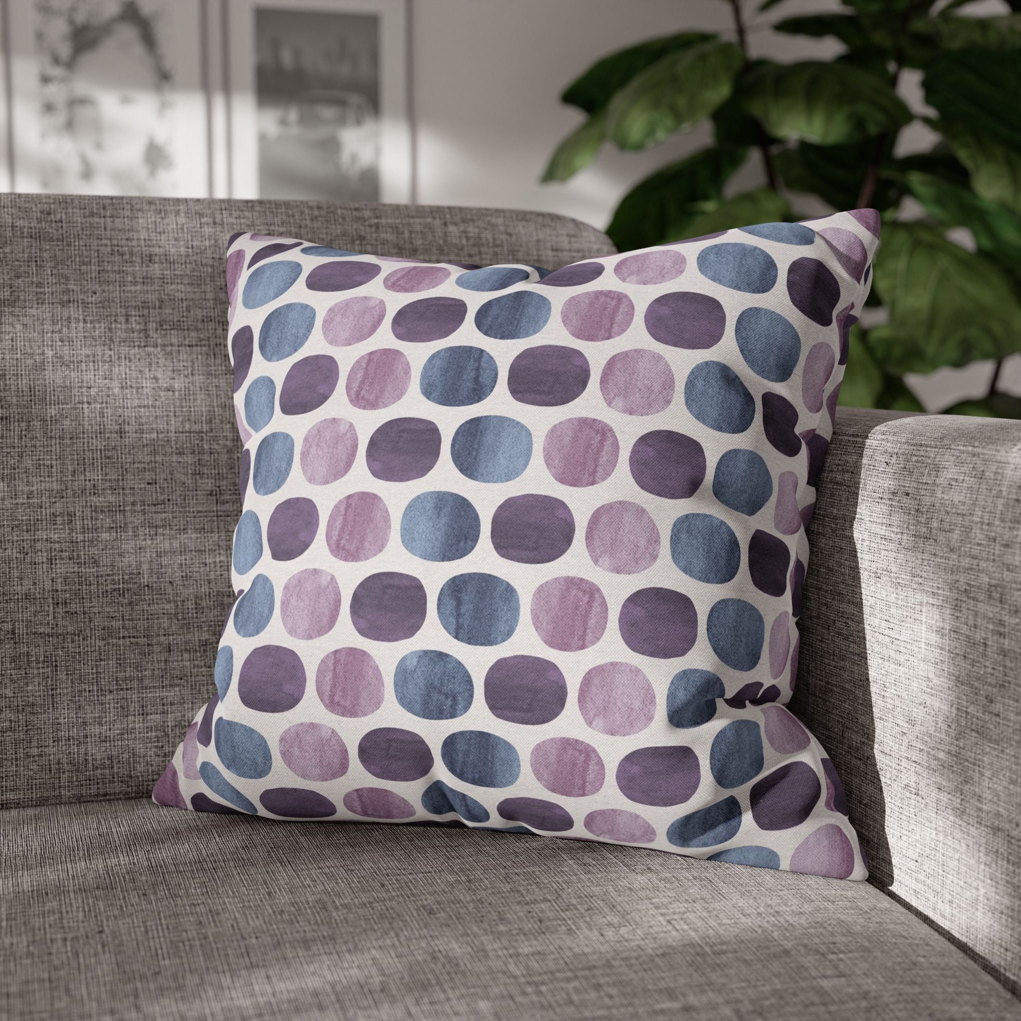 A gray couch with a colorful throw pillow featuring a pattern of purple and blue circles on a white background.