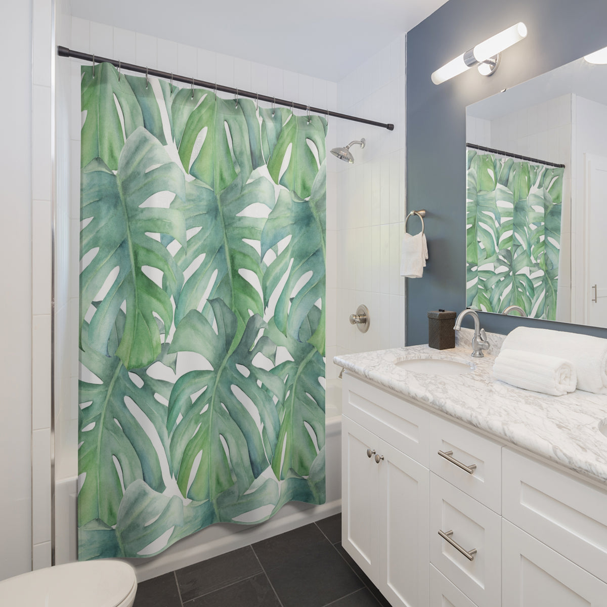 A bathroom with a white vanity, a shower curtain with a tropical leaf pattern, and a mirror above the sink.