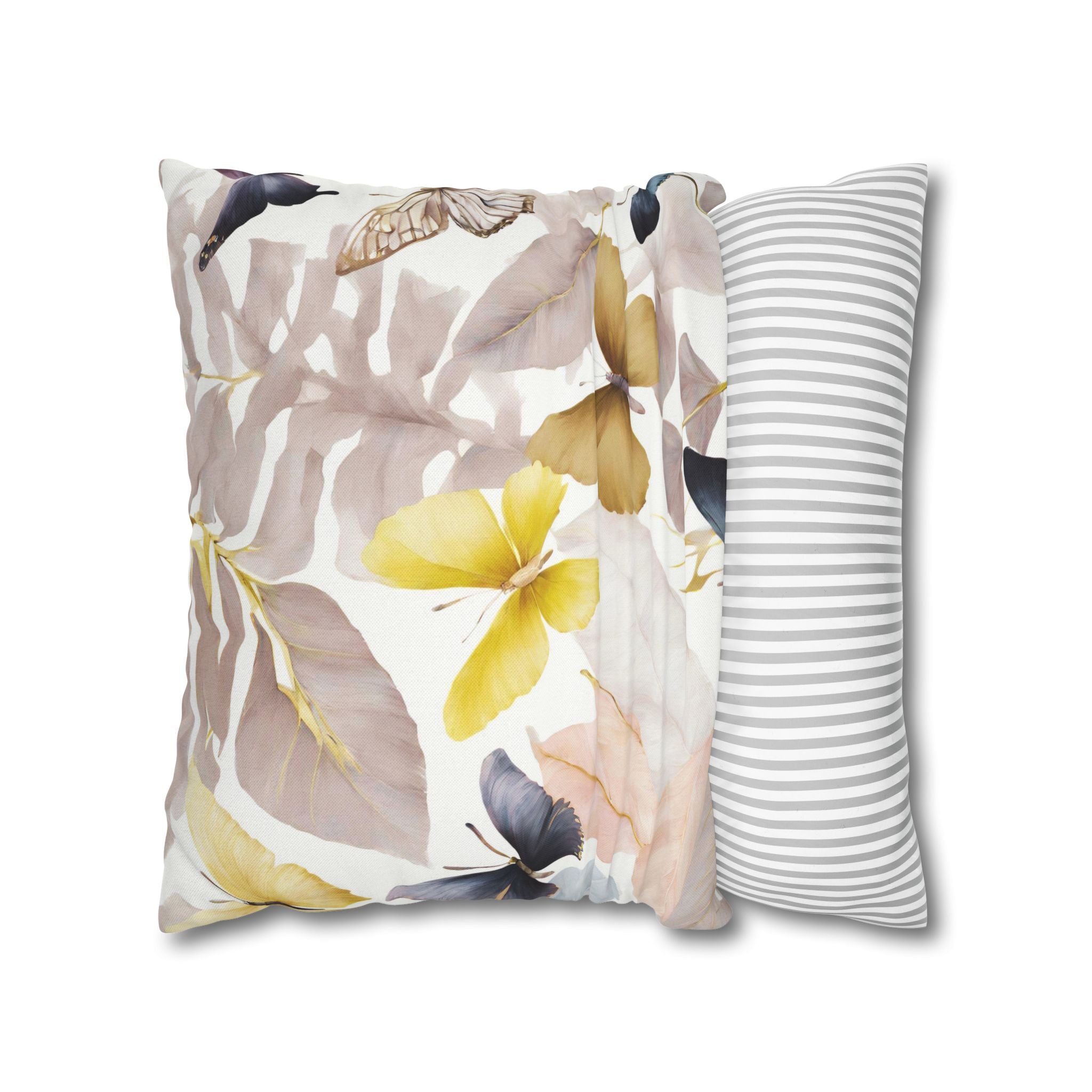 a decorative pillow with a floral pattern, including yellow and purple flowers, along with green leaves. The pillow is placed on a white background, and there is a striped pillow to the right of it.