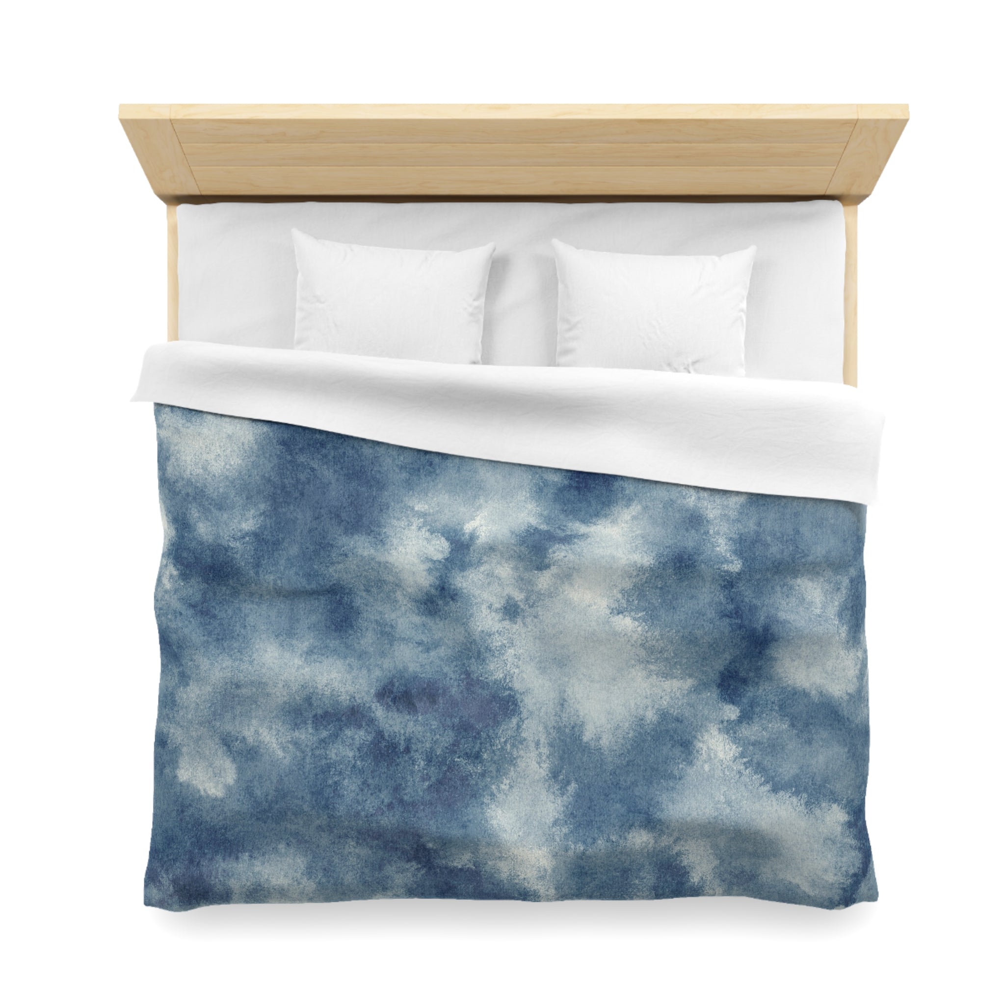 A neatly made bed with a blue and white patterned comforter and two white pillows.