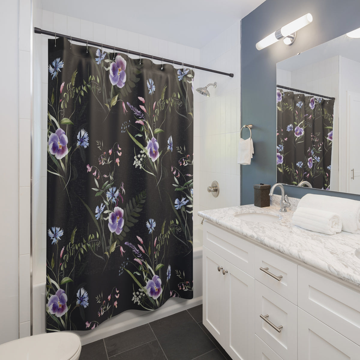 a modern bathroom with a black shower curtain featuring a floral pattern in shades of purple and blue. The bathroom has white cabinets, a marble countertop, and a white sink with a silver faucet.