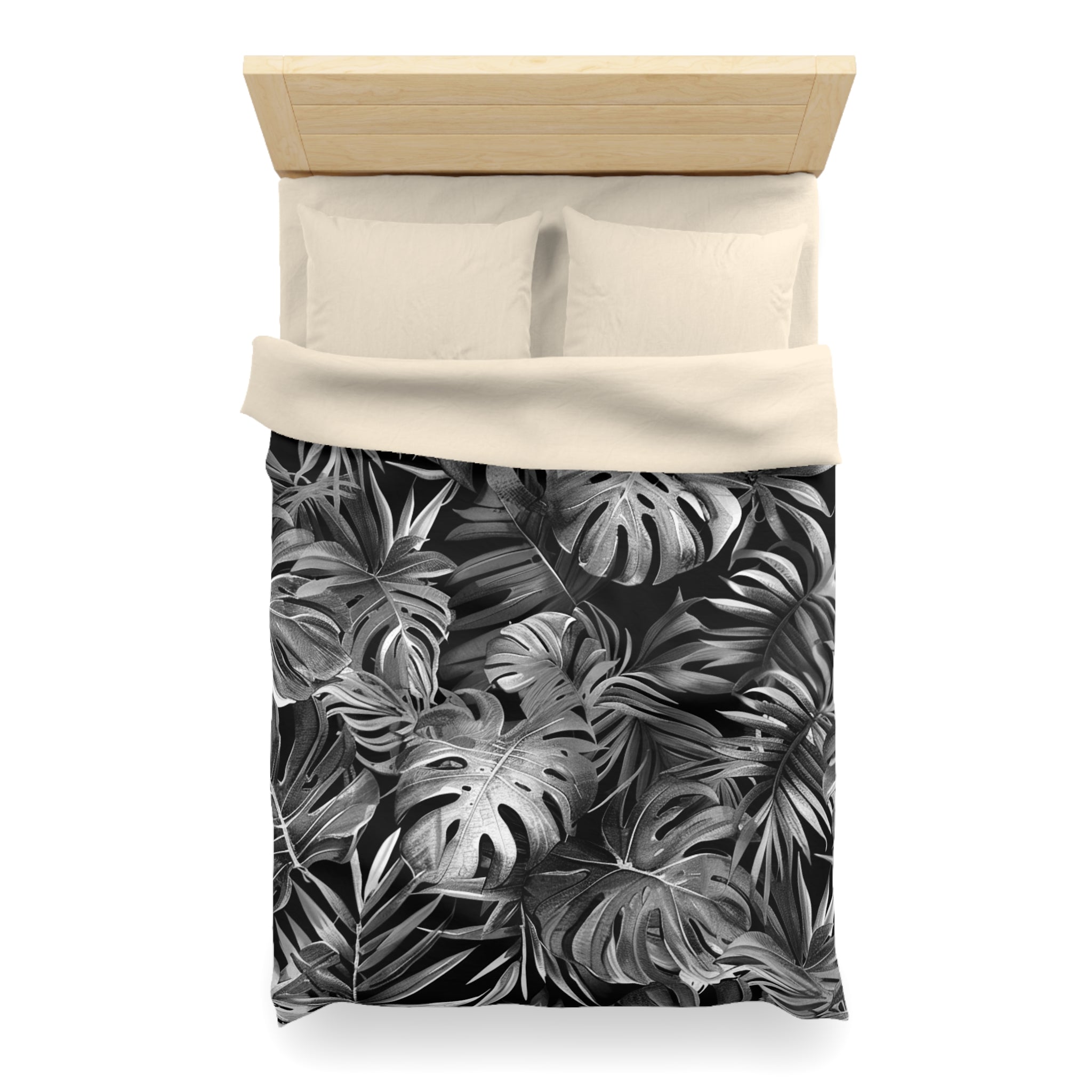 a bed with a black and white tropical leaf pattern on the comforter and pillowcases.