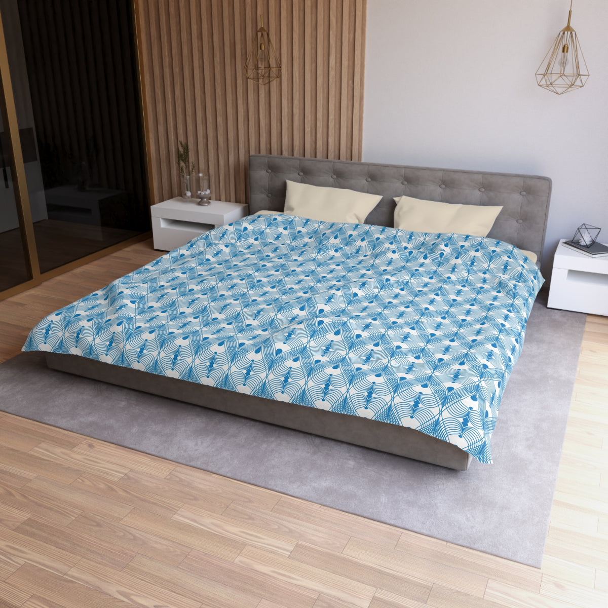 a modern bedroom with a large bed, a gray headboard, and a blue and white patterned comforter. The room has a wooden floor and white walls, creating a clean and minimalist aesthetic.