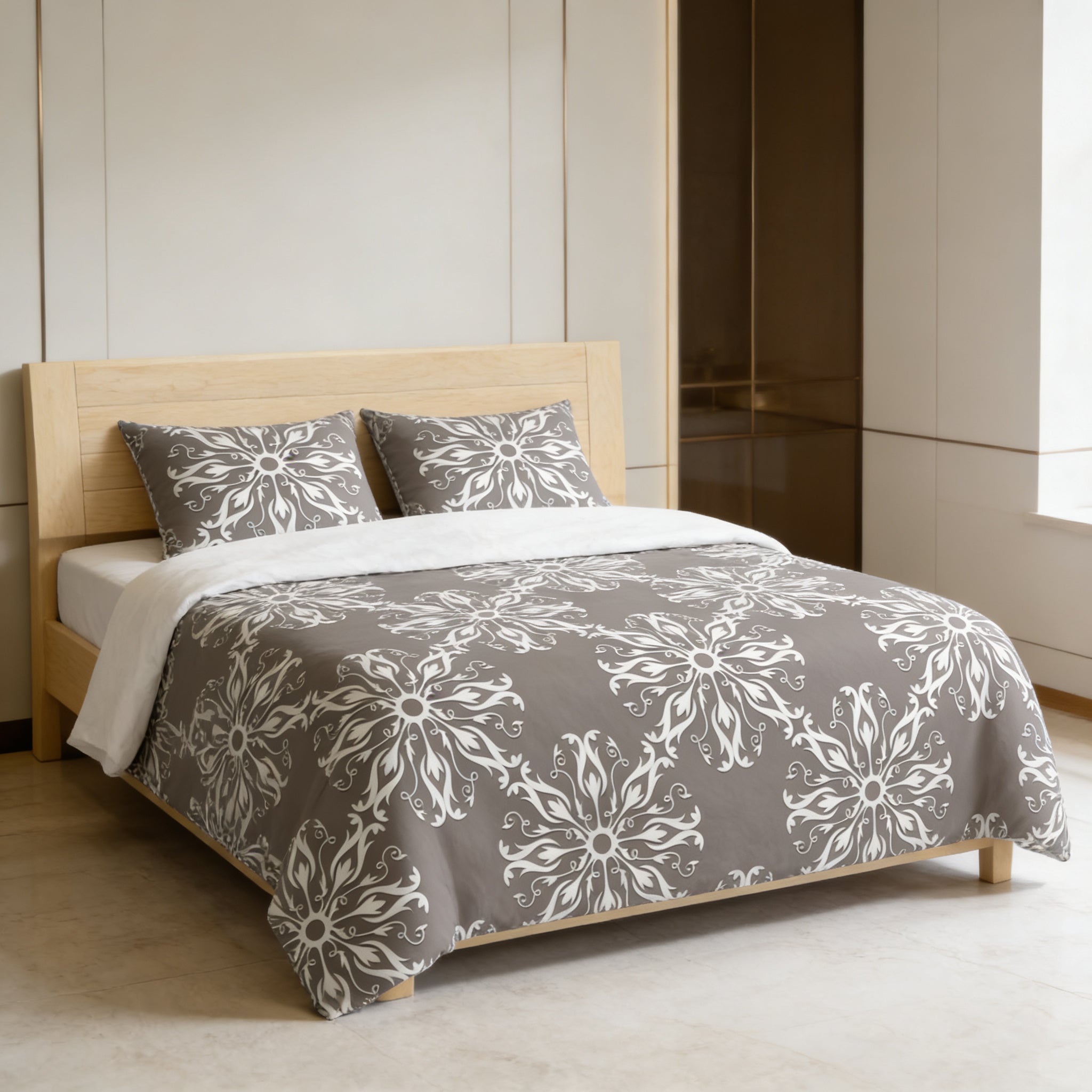 a modern bedroom with a bed featuring a gray and white floral patterned comforter and pillows. The bed is positioned against a white wall, and there is a window nearby.