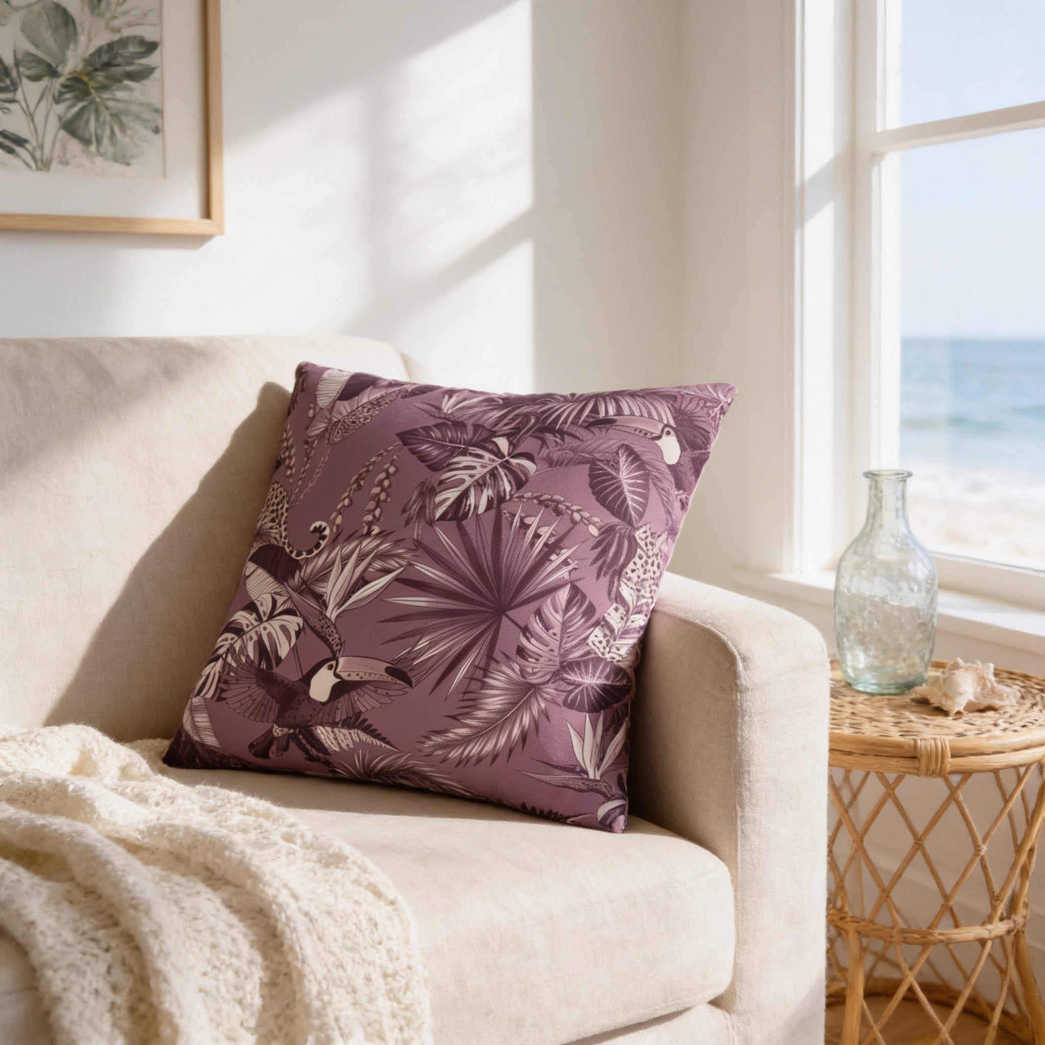 a cozy living room with a beige sofa, a purple throw pillow with a tropical leaf pattern, and a woven side table with a glass vase and a seashell.