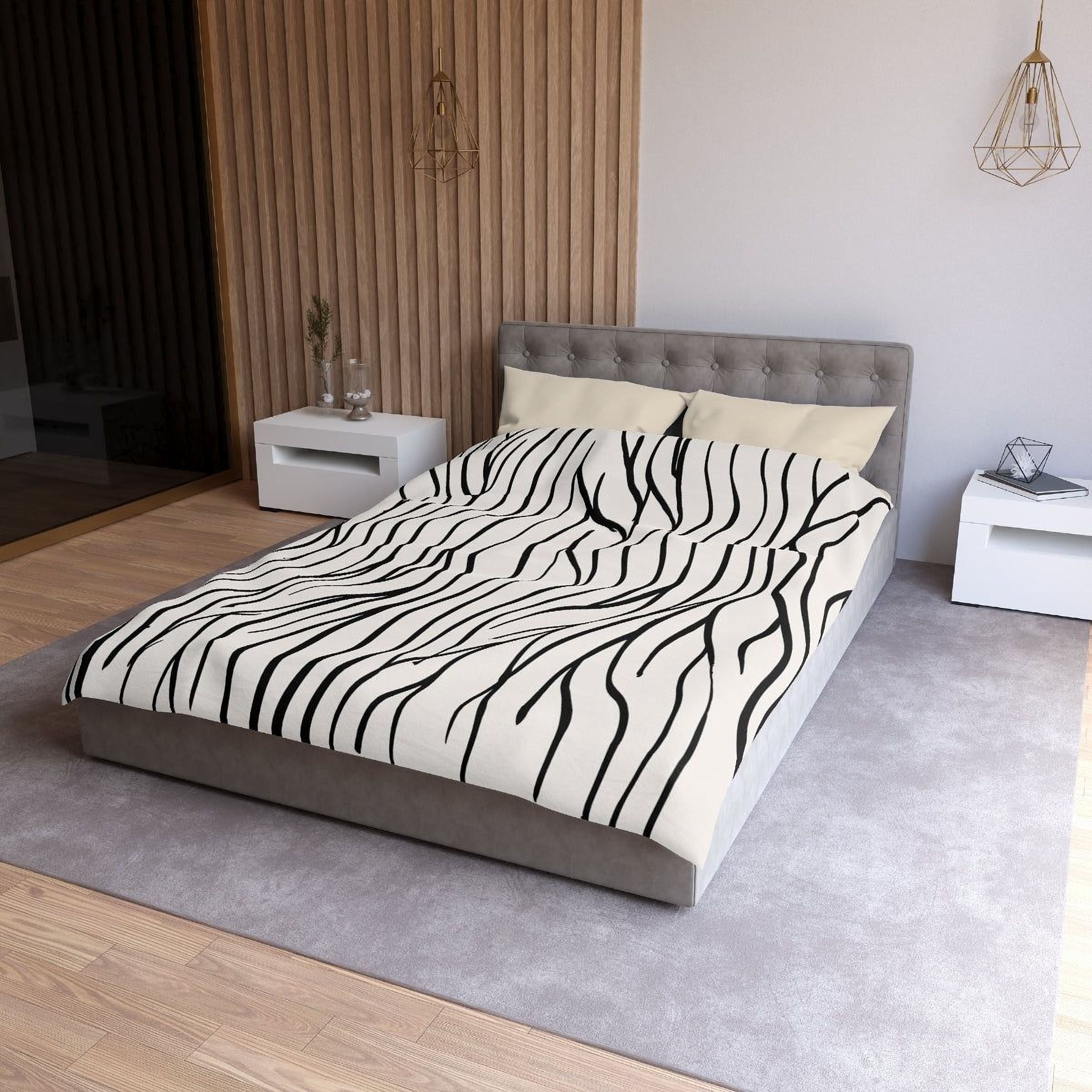 a modern bedroom with a gray tufted headboard, a black and white zebra-patterned comforter, and white nightstands.