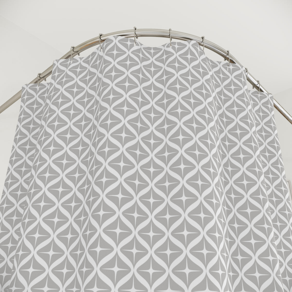 a shower curtain with a repeating pattern of gray and white stars and lines, hanging from a curved metal rod.