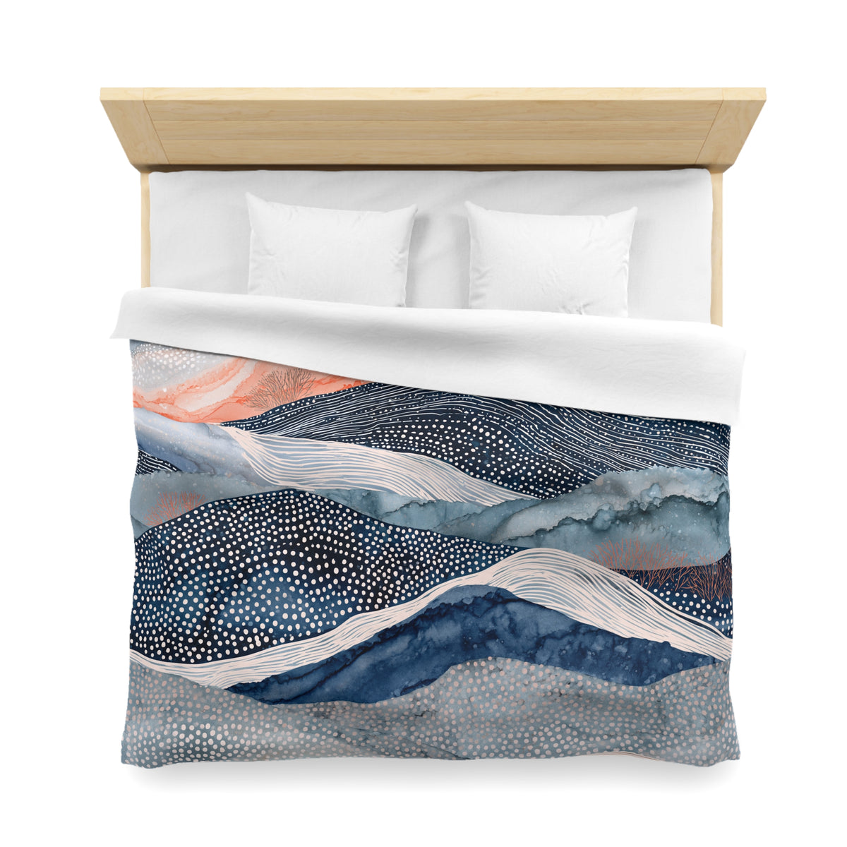 a bed with a decorative comforter featuring a mountain landscape design in shades of blue, white, and orange.