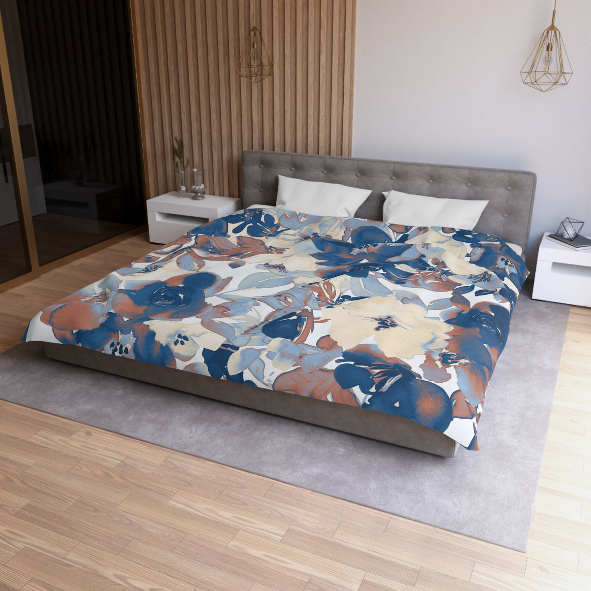 a modern bedroom with a large bed covered in a floral print comforter. The bed is positioned against a wall with a wooden panel. The room has a gray headboard and a white nightstand on each side of the bed. The floor is covered with a gray rug.