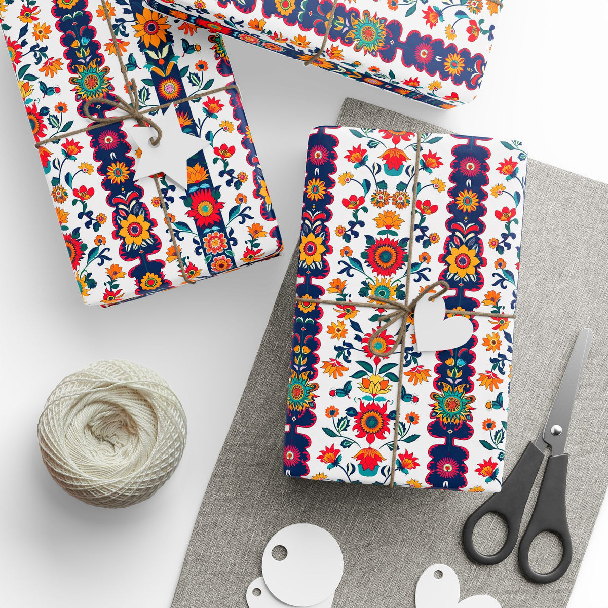 Red, navy and white folk floral wrapping paper on gifts tied with twine, with gift tags and scissors