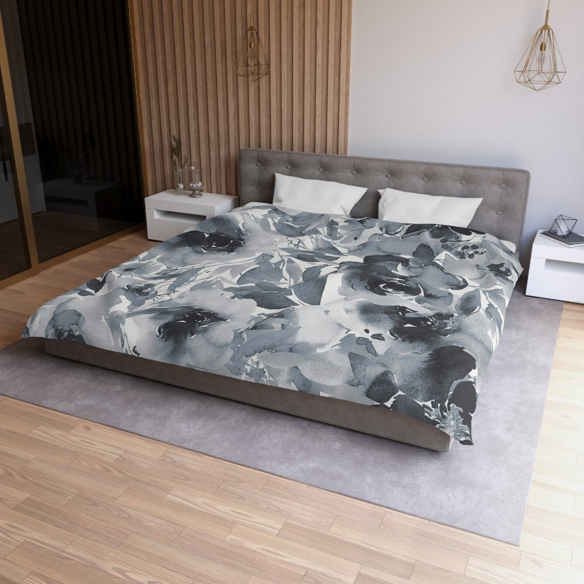 a modern bedroom with a large bed, a gray headboard, and a gray and white floral patterned comforter. The room has a wooden floor and white walls, creating a serene and elegant atmosphere.