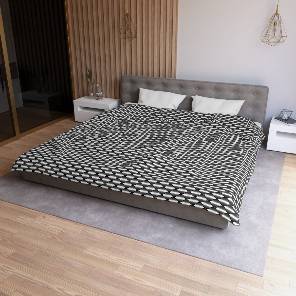 a modern bedroom with a large bed, a gray headboard, and a black and white patterned comforter. The room has a wooden floor and white walls, creating a clean and minimalist aesthetic.