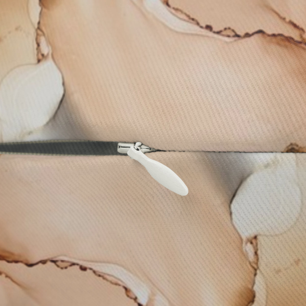 A close-up view of a zipper on a fabric, with a white plastic zipper pull visible.