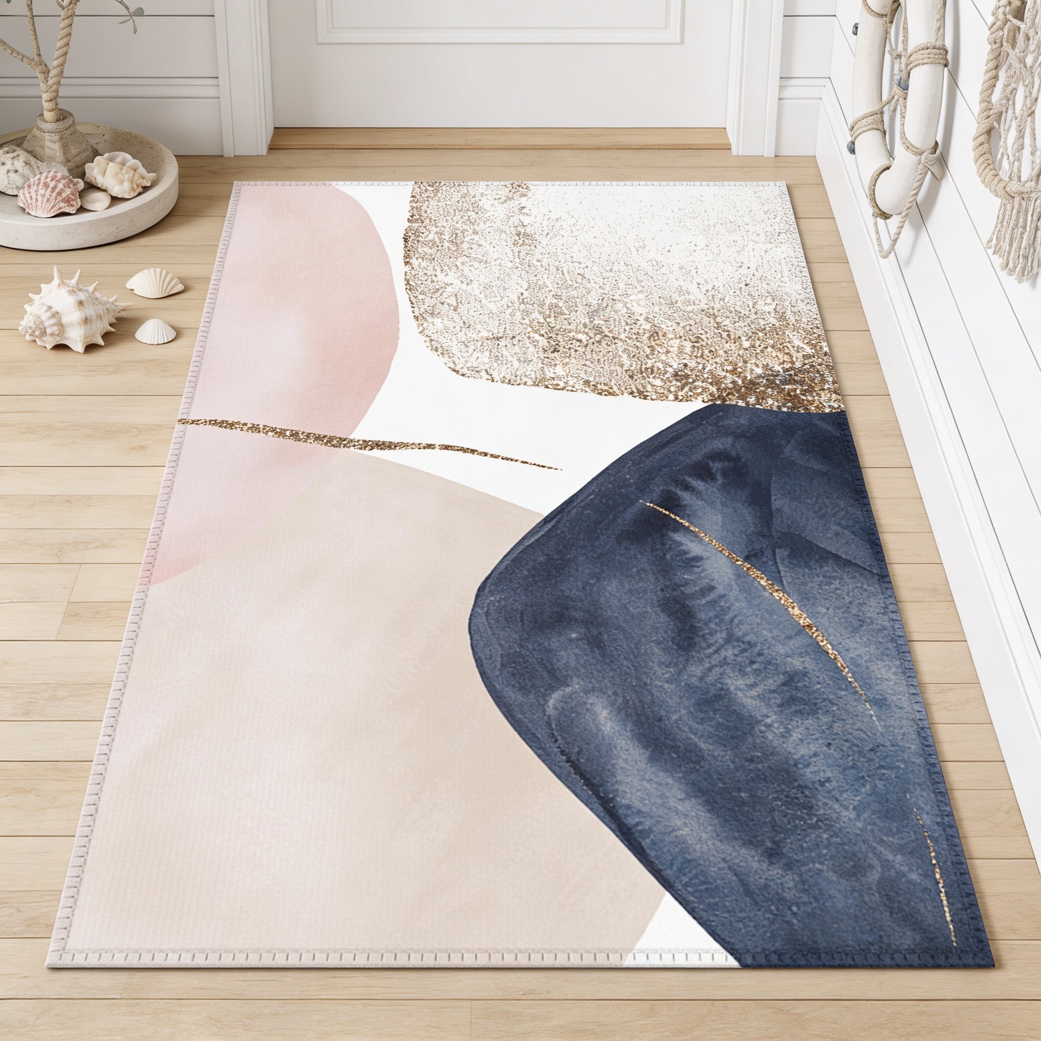 a rug with abstract geometric patterns in shades of pink, blue, and white. The rug is placed on a wooden floor, and there are some seashells and a rope decoration nearby.