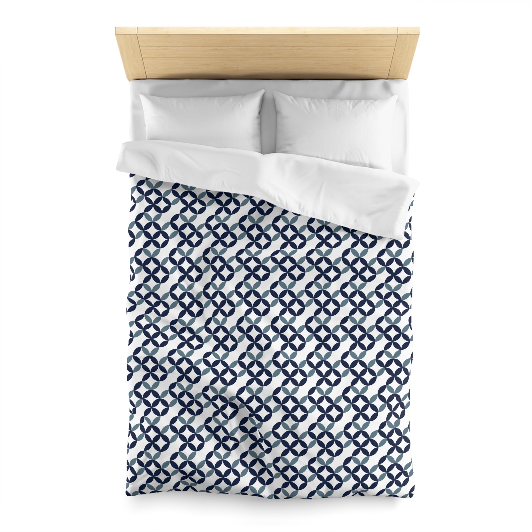 a neatly made bed with a blue and white patterned comforter and two white pillows.