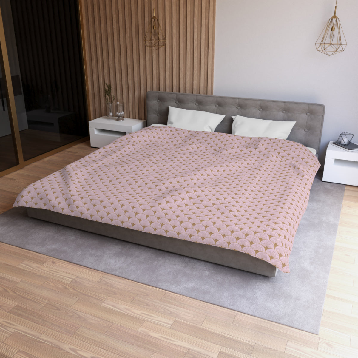 a modern bedroom with a large bed, a gray headboard, and a pink and gold patterned comforter. The room has a wooden floor and white walls, creating a clean and minimalist aesthetic.