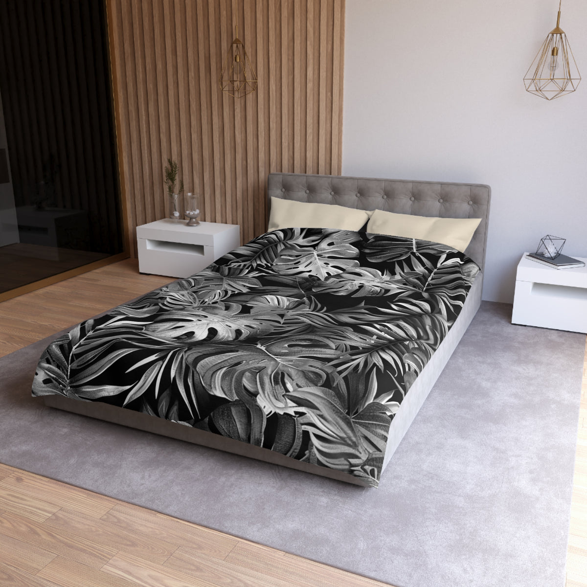 a modern bedroom with a large bed covered in a black and white tropical leaf patterned comforter. The bed is positioned against a wall with a wooden panel design. The room also includes white nightstands and a gray area rug, creating a cohesive and stylish interior design.