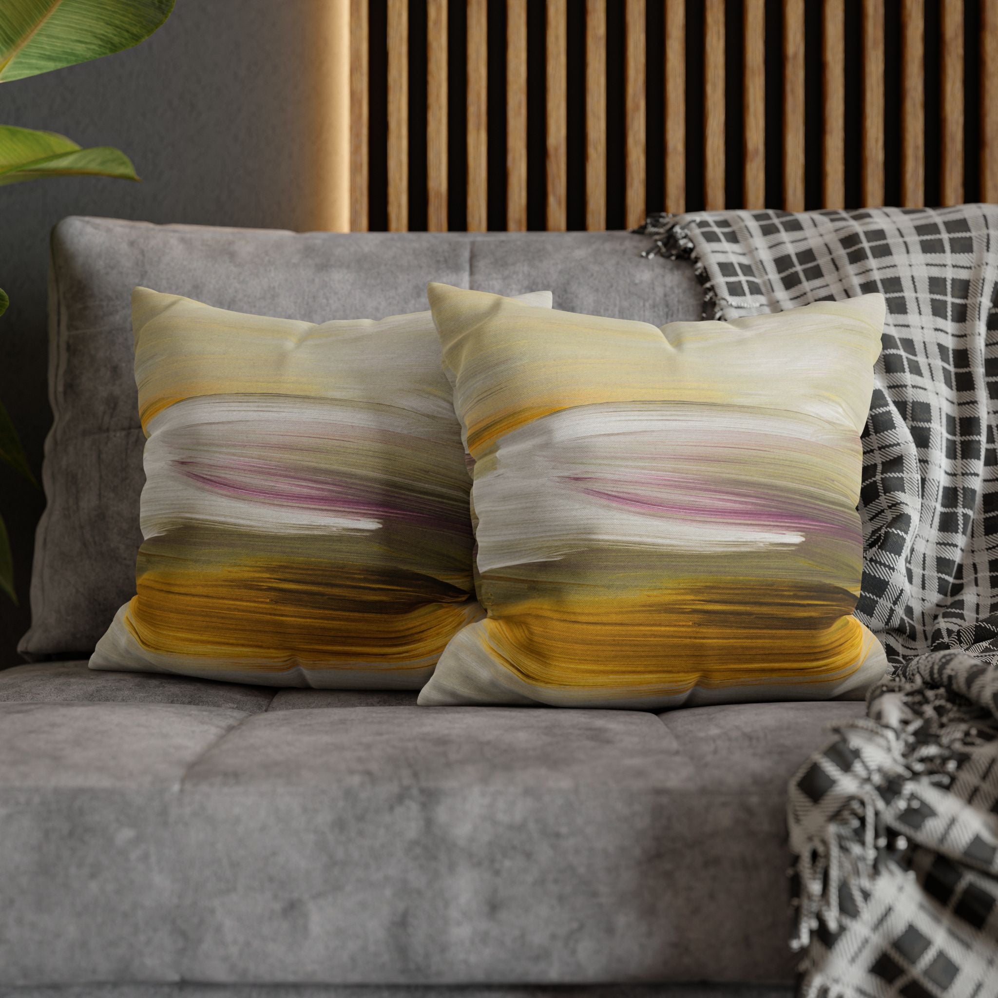 a gray couch with two throw pillows featuring a colorful abstract design in shades of yellow, pink, and white.