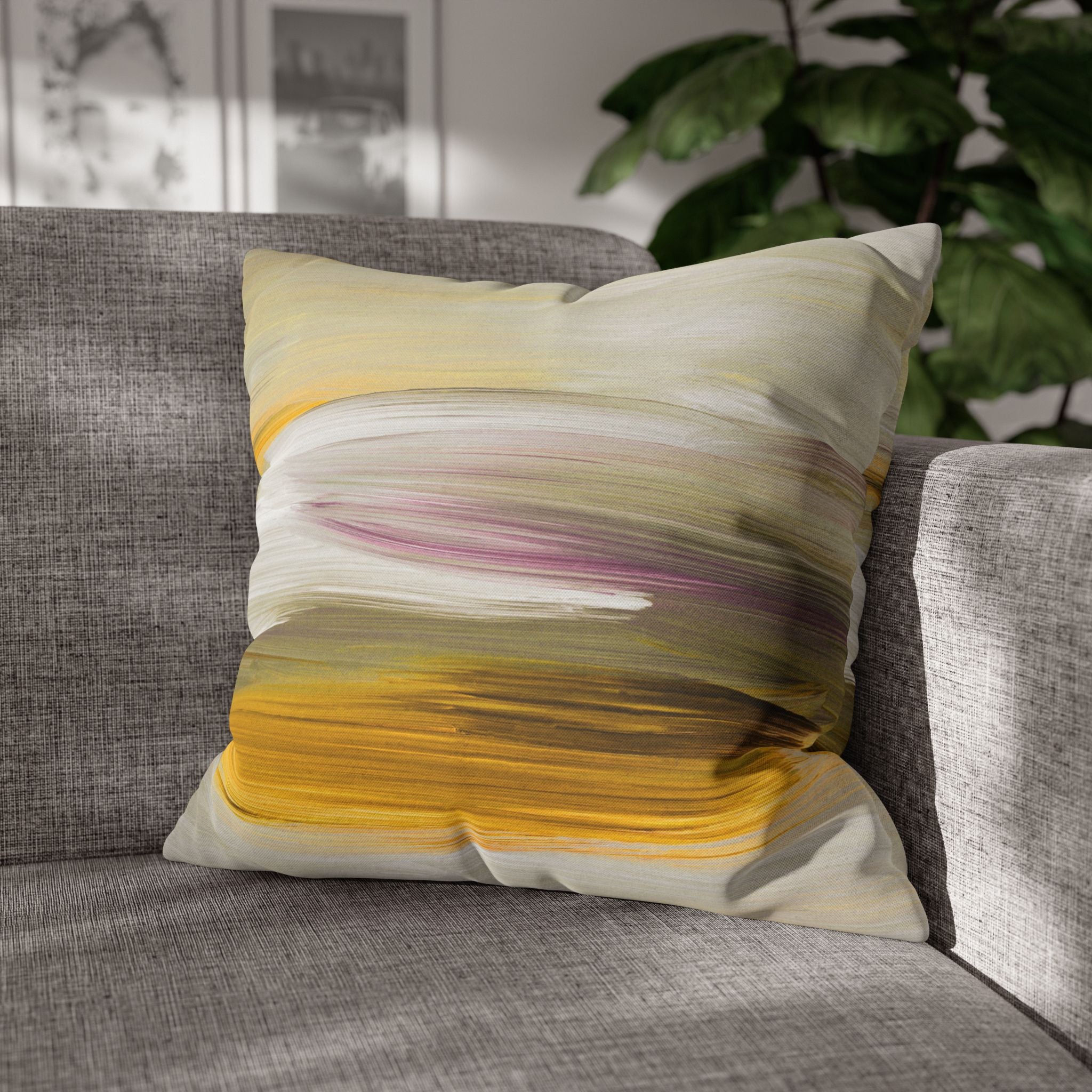 a gray couch with a colorful throw pillow featuring a vibrant abstract design in shades of yellow, pink, and green.