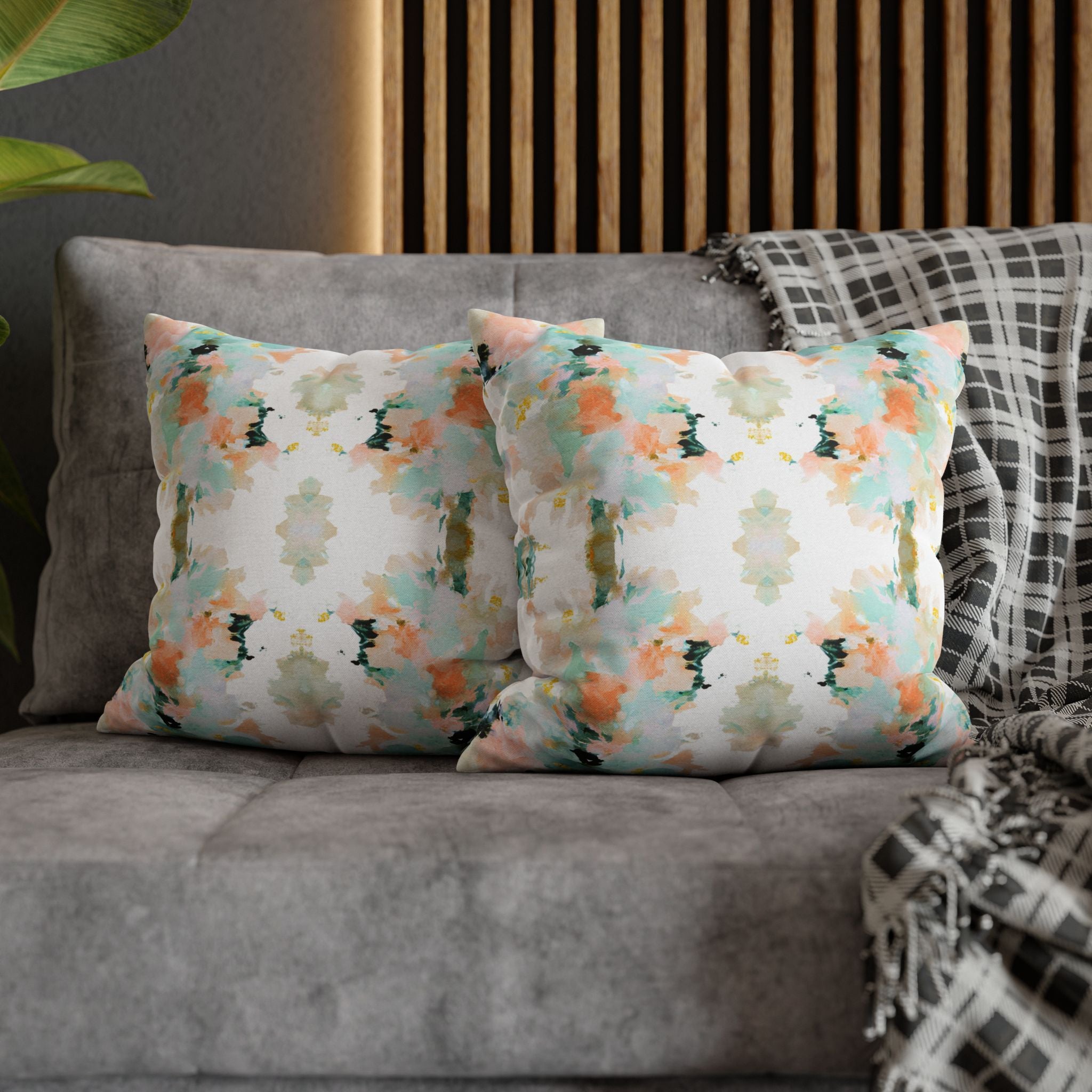 a gray couch with two throw pillows on it. The pillows have a colorful, abstract pattern in shades of green, orange, and white. The pillows are placed on the couch, creating a cozy and inviting atmosphere.