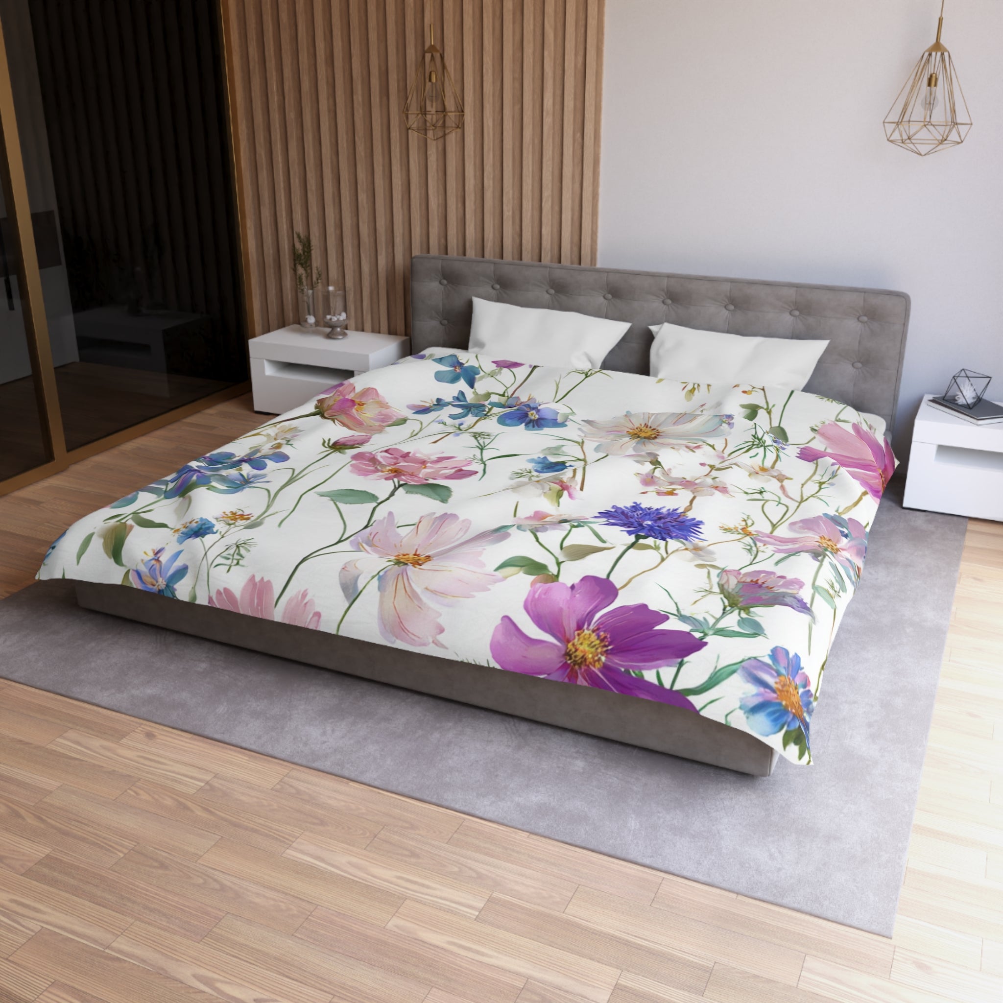 a bedroom with a large bed covered in a floral comforter featuring pink and purple flowers. The bed is positioned against a wall with a wooden panel. The room also includes a nightstand and a pendant light fixture.