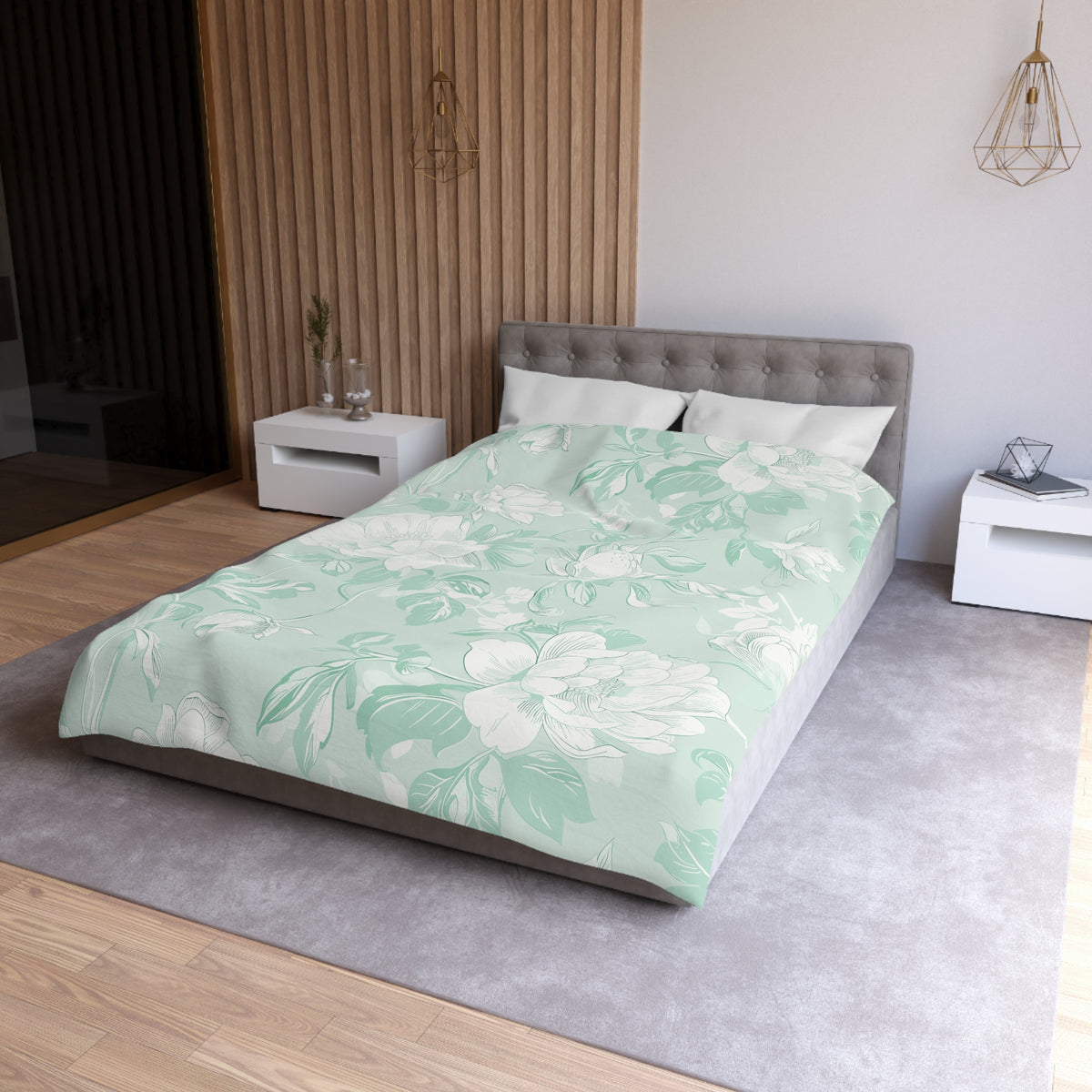 a modern bedroom with a large bed, white nightstands, and a gray headboard. The bed is covered in a floral print comforter, and the room has a neutral color scheme with a gray carpet and wooden paneling on the walls.