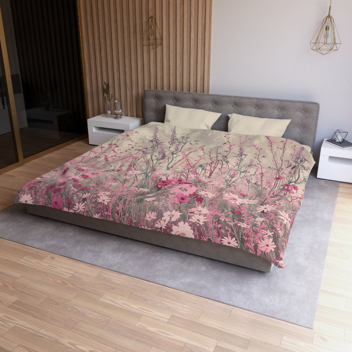 a bedroom with a large bed covered in a floral print comforter. The bed is positioned against a wall with a wooden panel. The room has a wooden floor and a white nightstand on the left side of the bed. There is also a pendant light hanging above the bed.