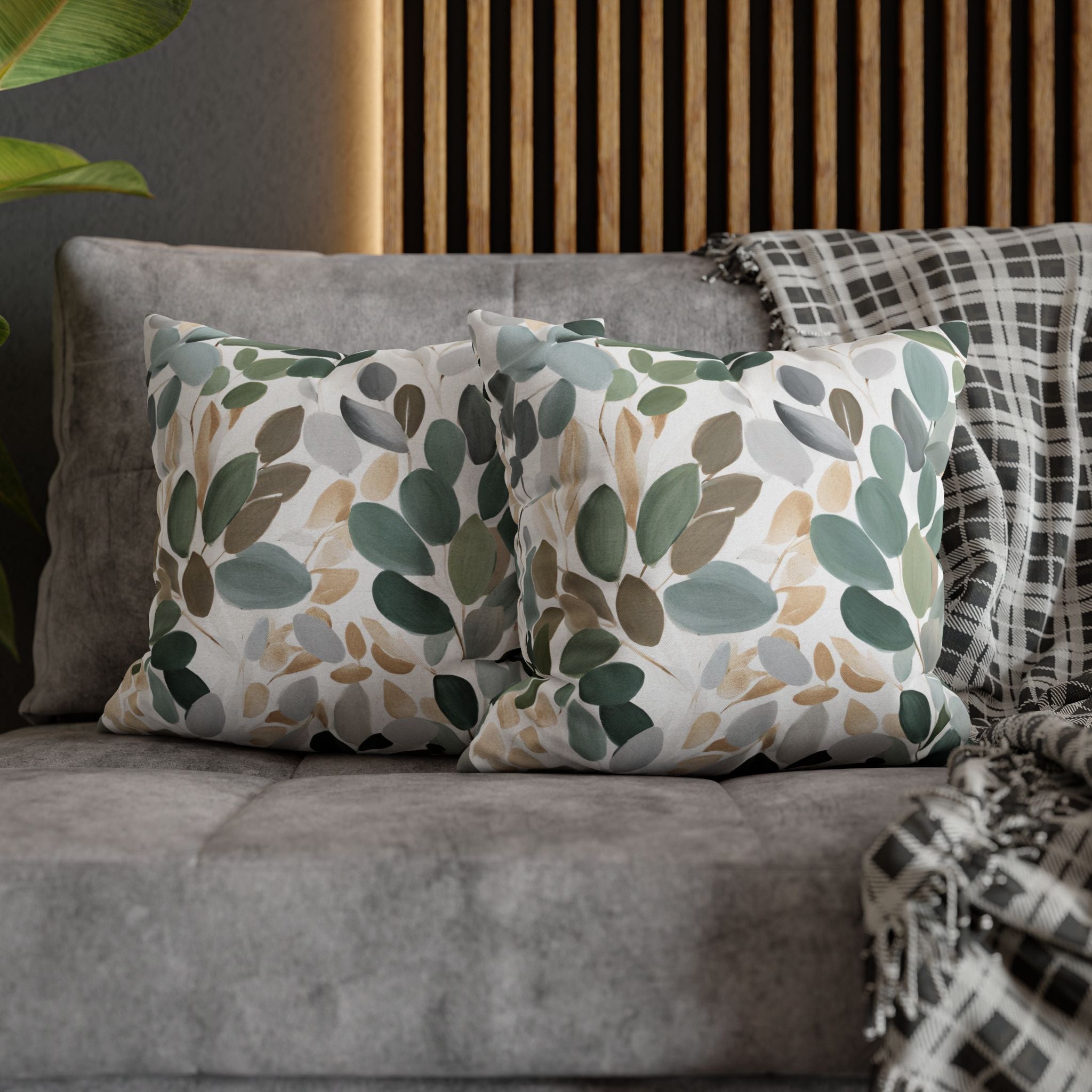 a gray couch with two throw pillows featuring a leaf pattern in shades of green and brown. The pillows are placed on the couch, creating a cozy and inviting atmosphere.